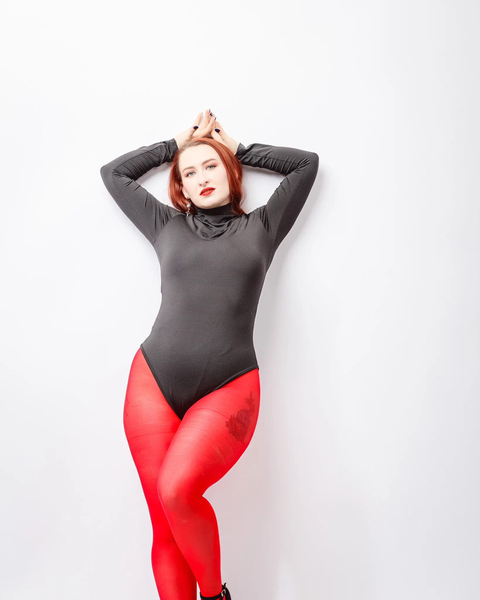 Person posing in red tights and black top.