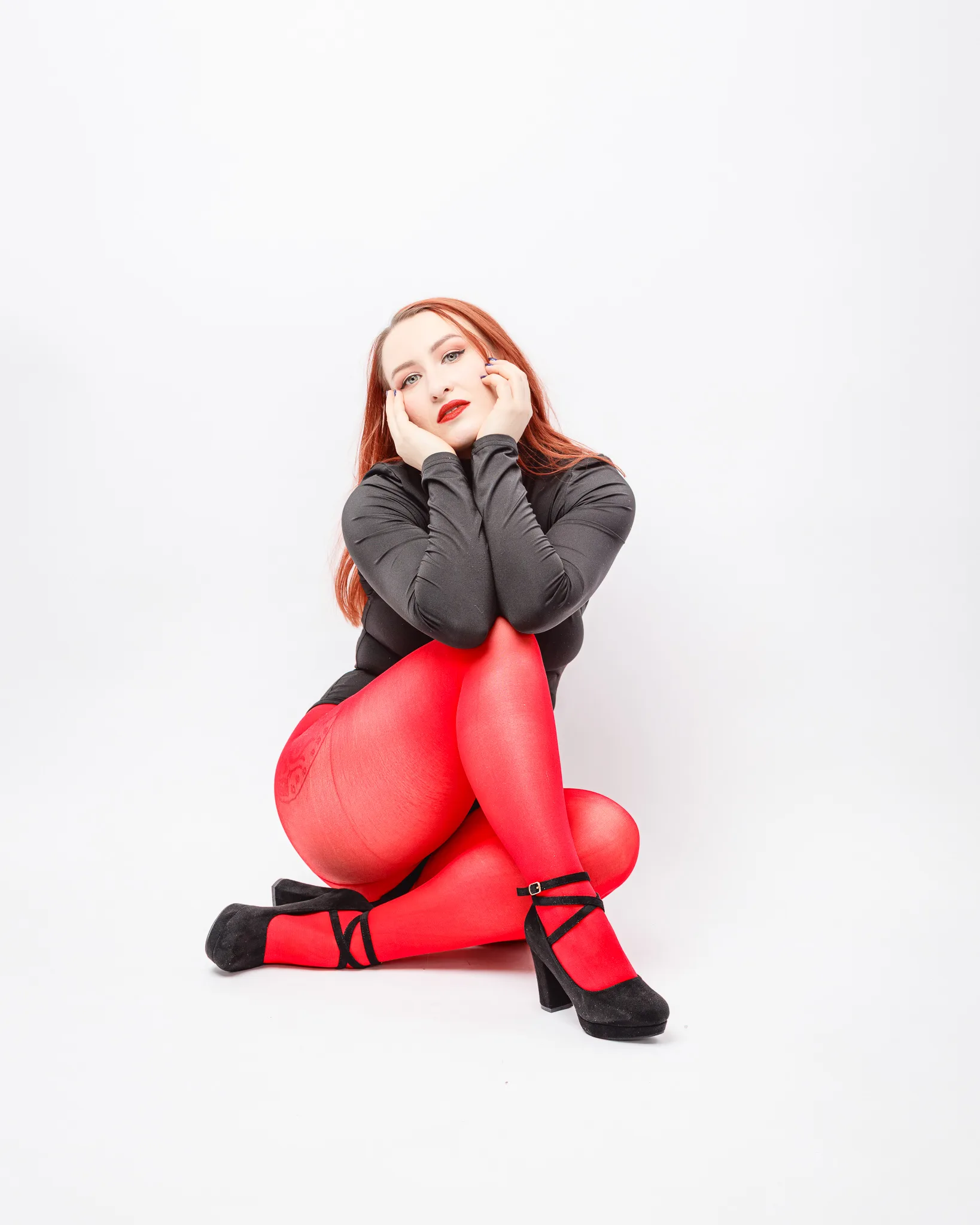 Woman in red tights and black outfit seated