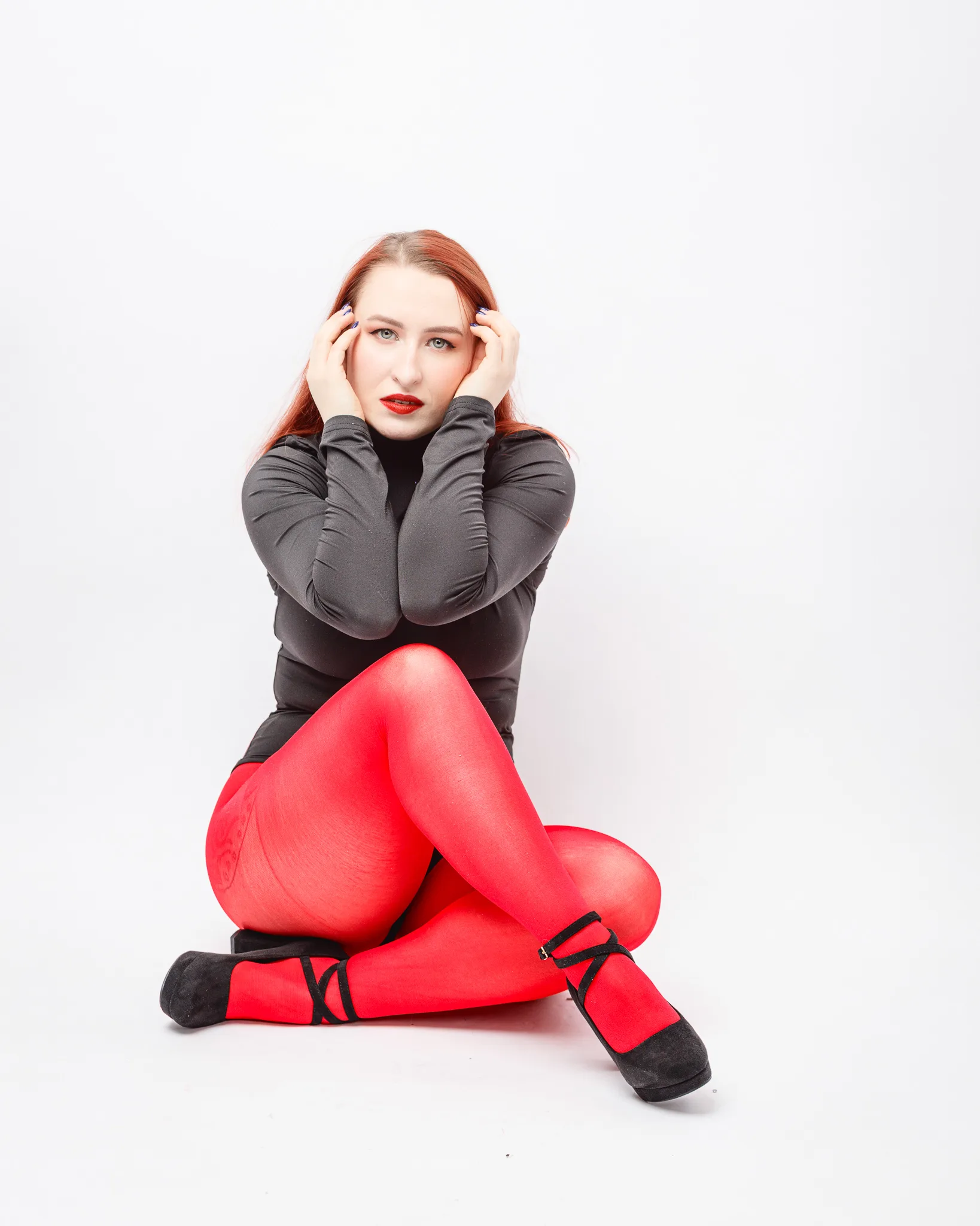 Person wearing red tights and black top sitting.