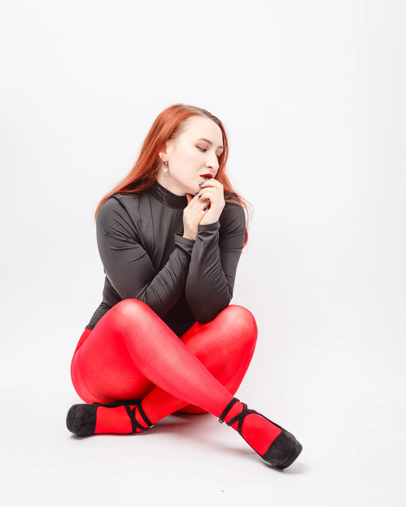 Woman in red tights and black top sitting.