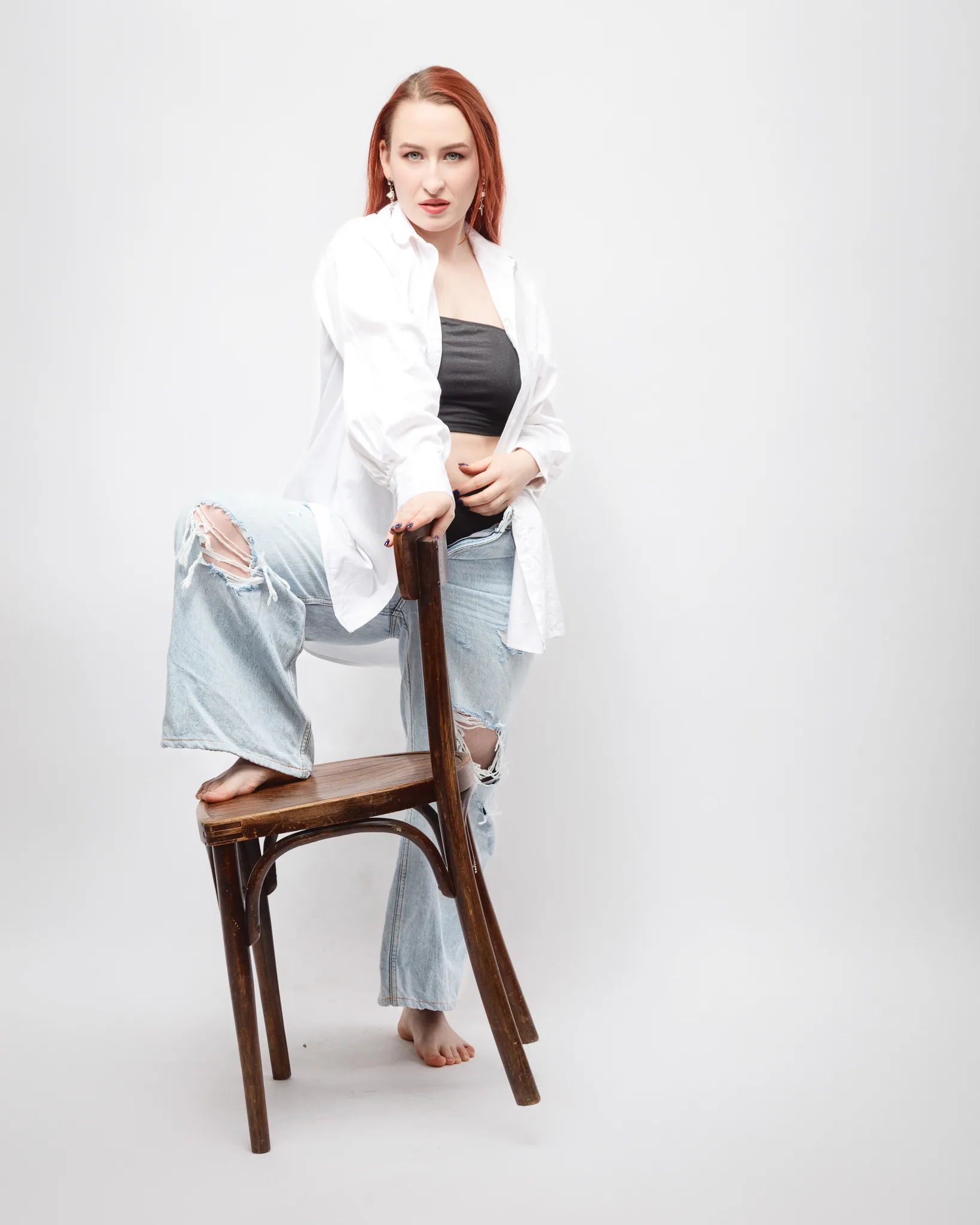 Person posing confidently on wooden chair.