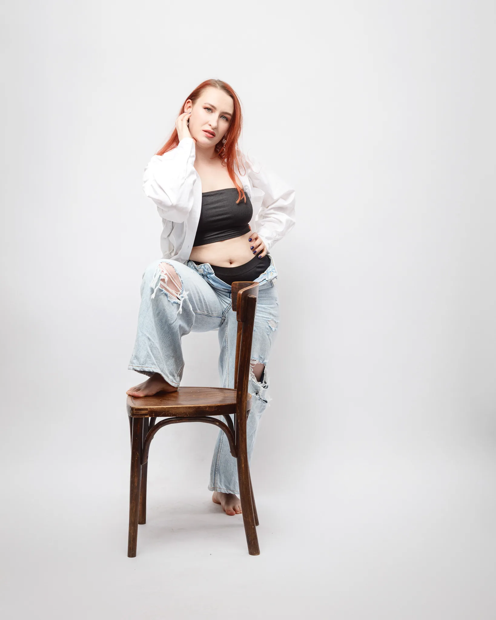 Person posing barefoot with chair, casual outfit.