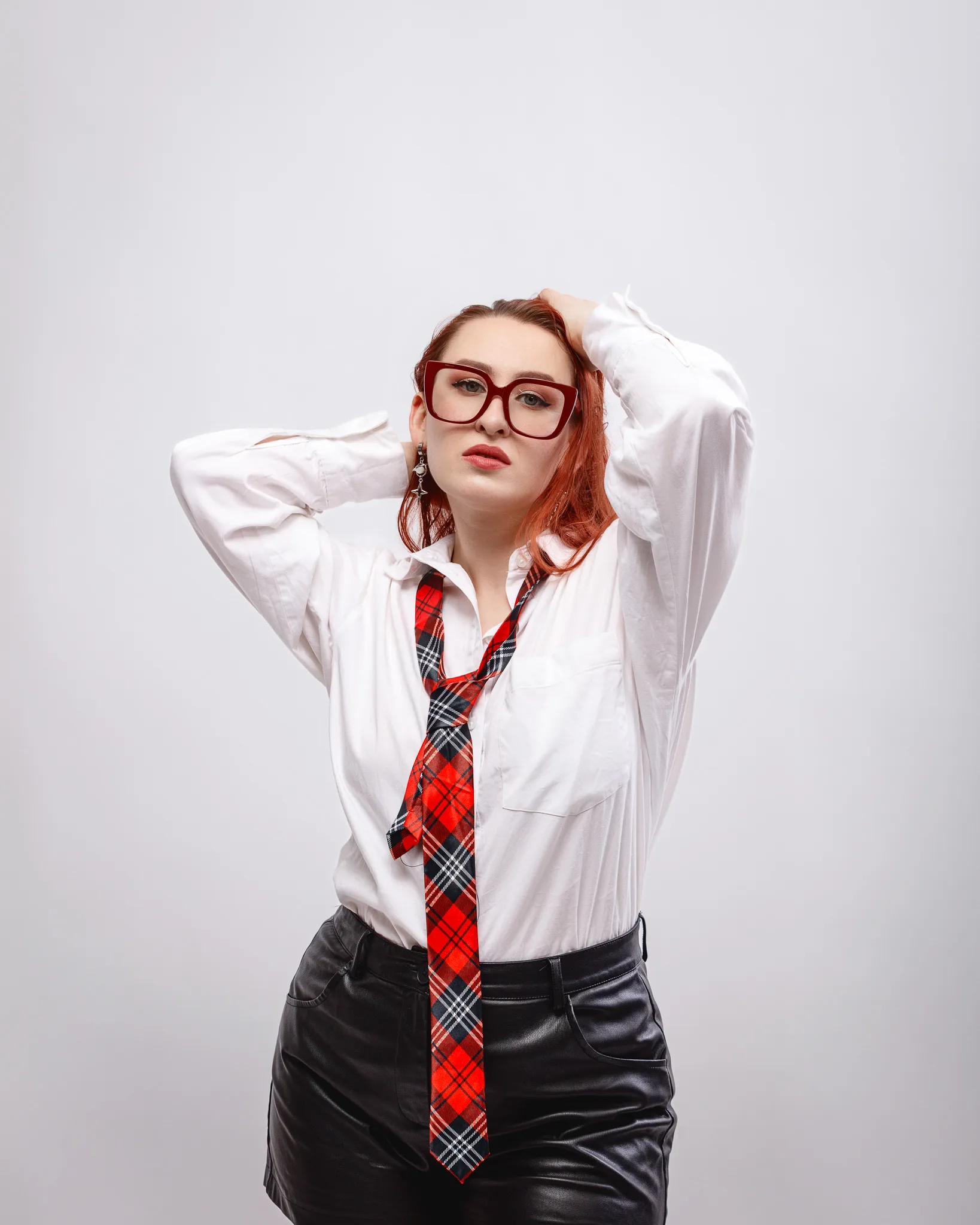 Woman in glasses wearing plaid tie and white shirt.