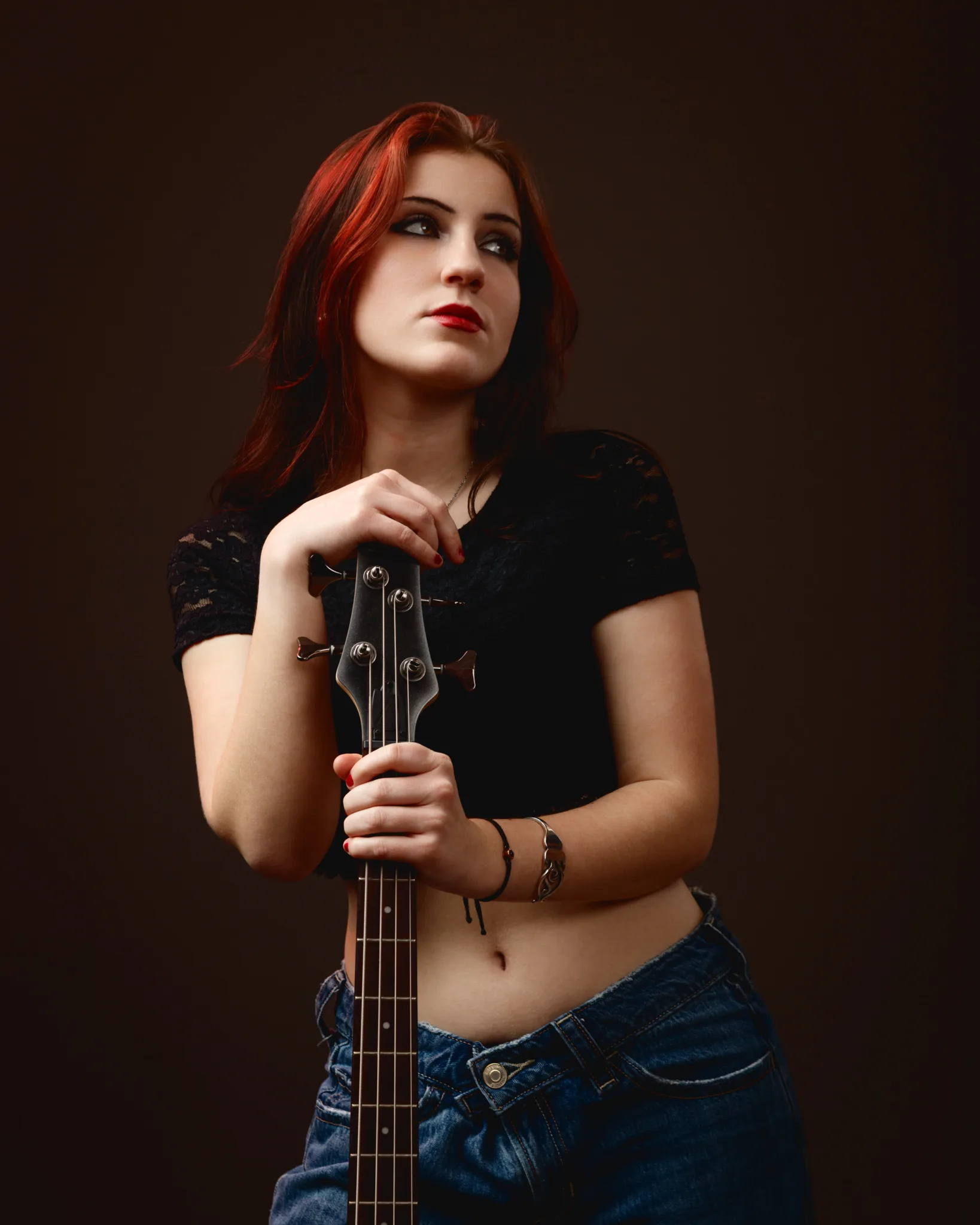 Woman holding a guitar in casual attire.