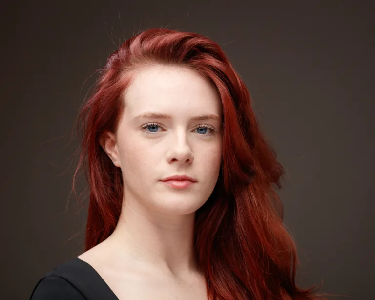 Woman with long red hair and neutral expression