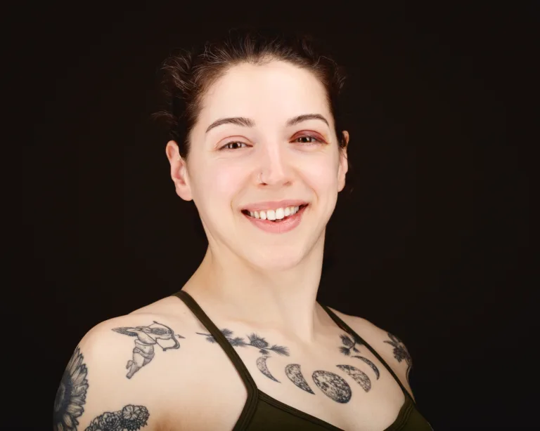 Smiling woman with tattoos on dark background