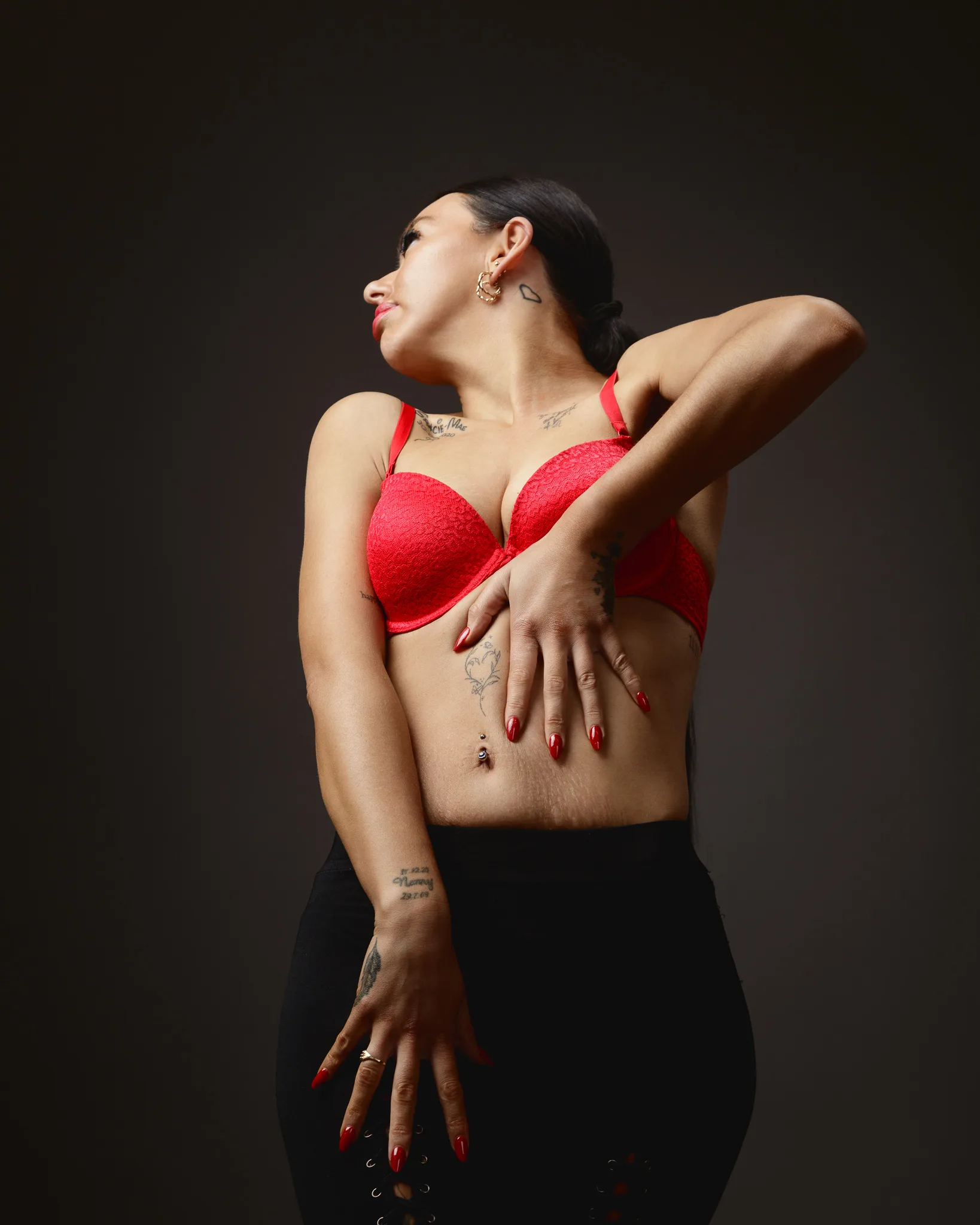 Woman posing in red bra with tattoos.
