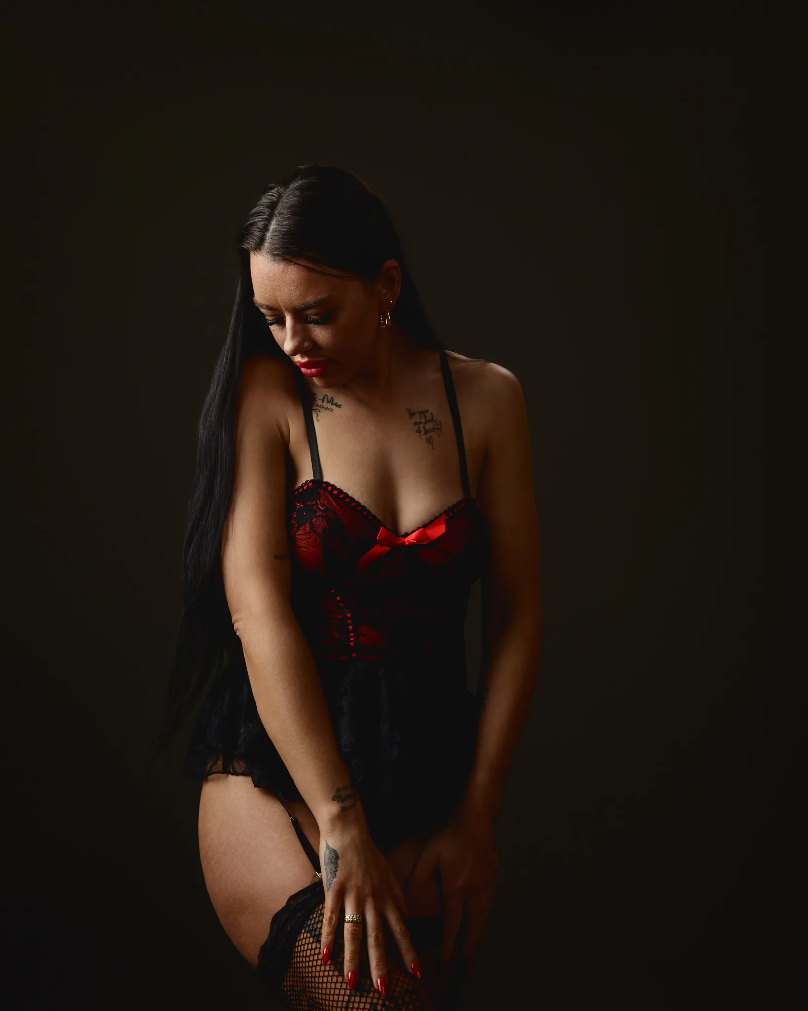 Woman in red and black lingerie posing.