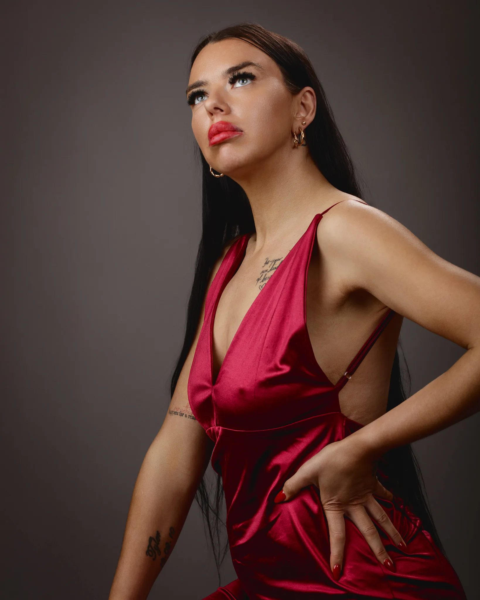 Woman posing in red dress with tattoos