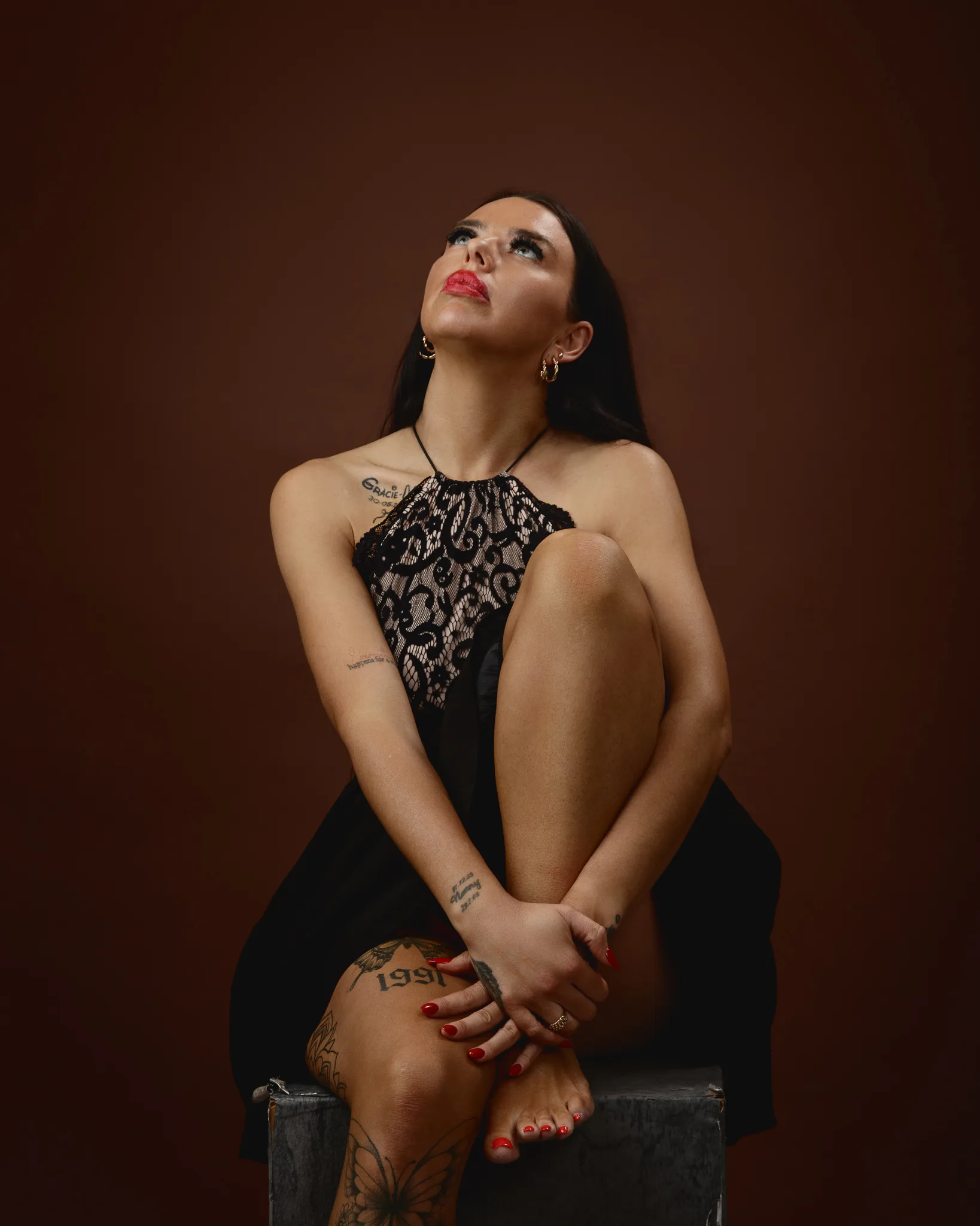 Woman in black lace dress looking up.