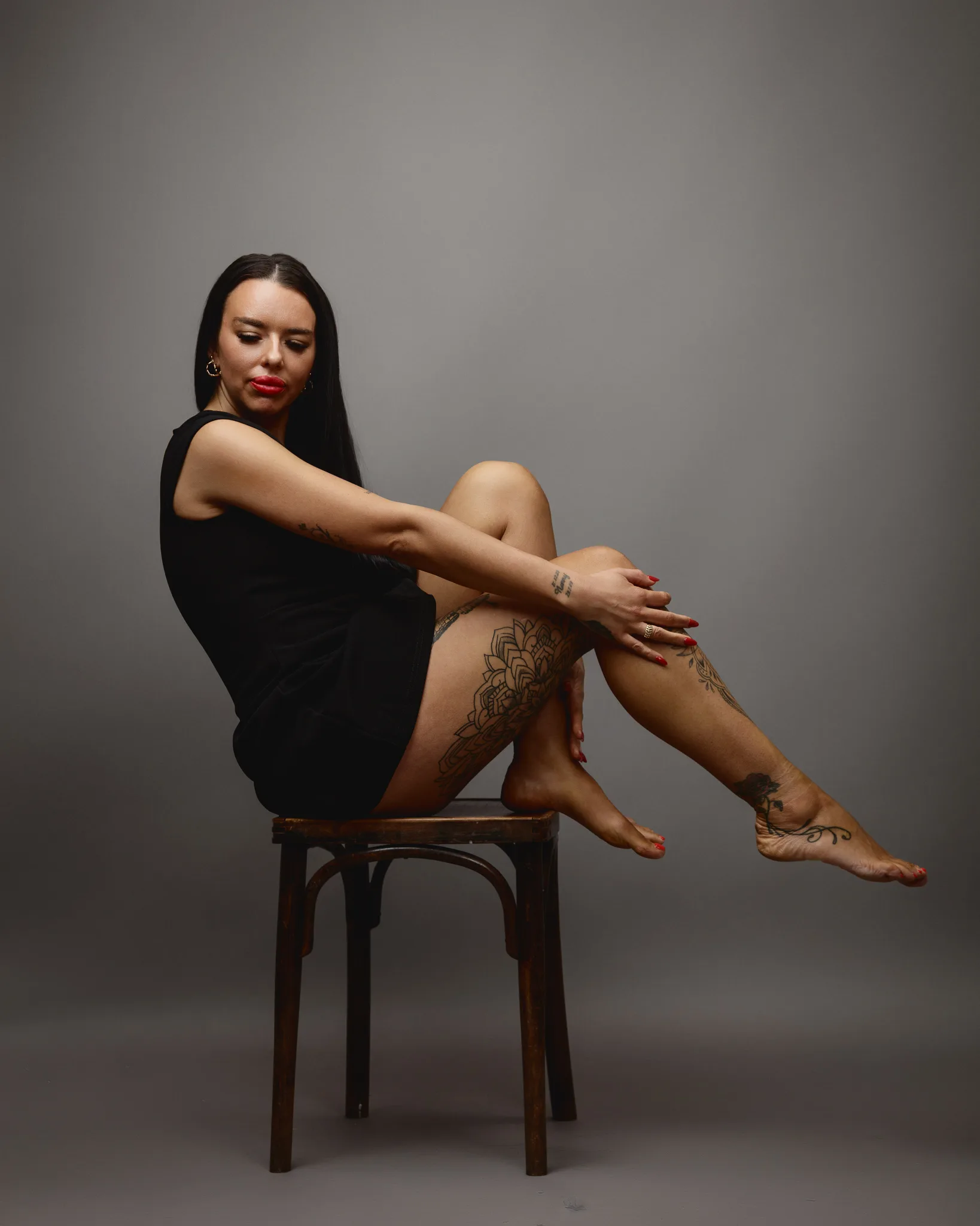 Tattooed woman sitting on a wooden chair.