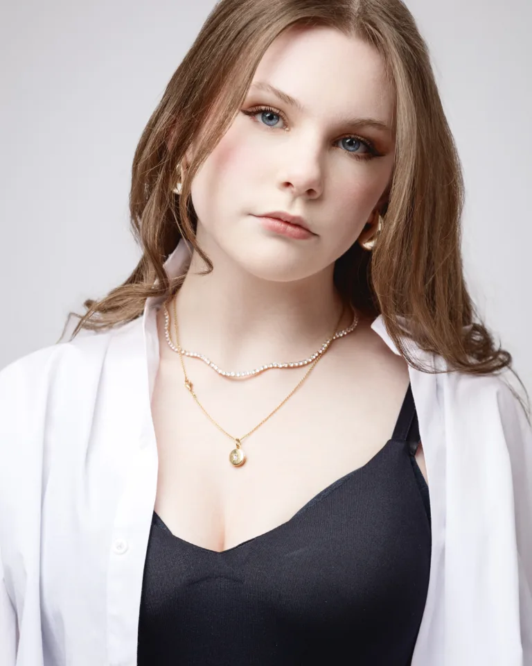 Woman wearing layered necklaces and white shirt