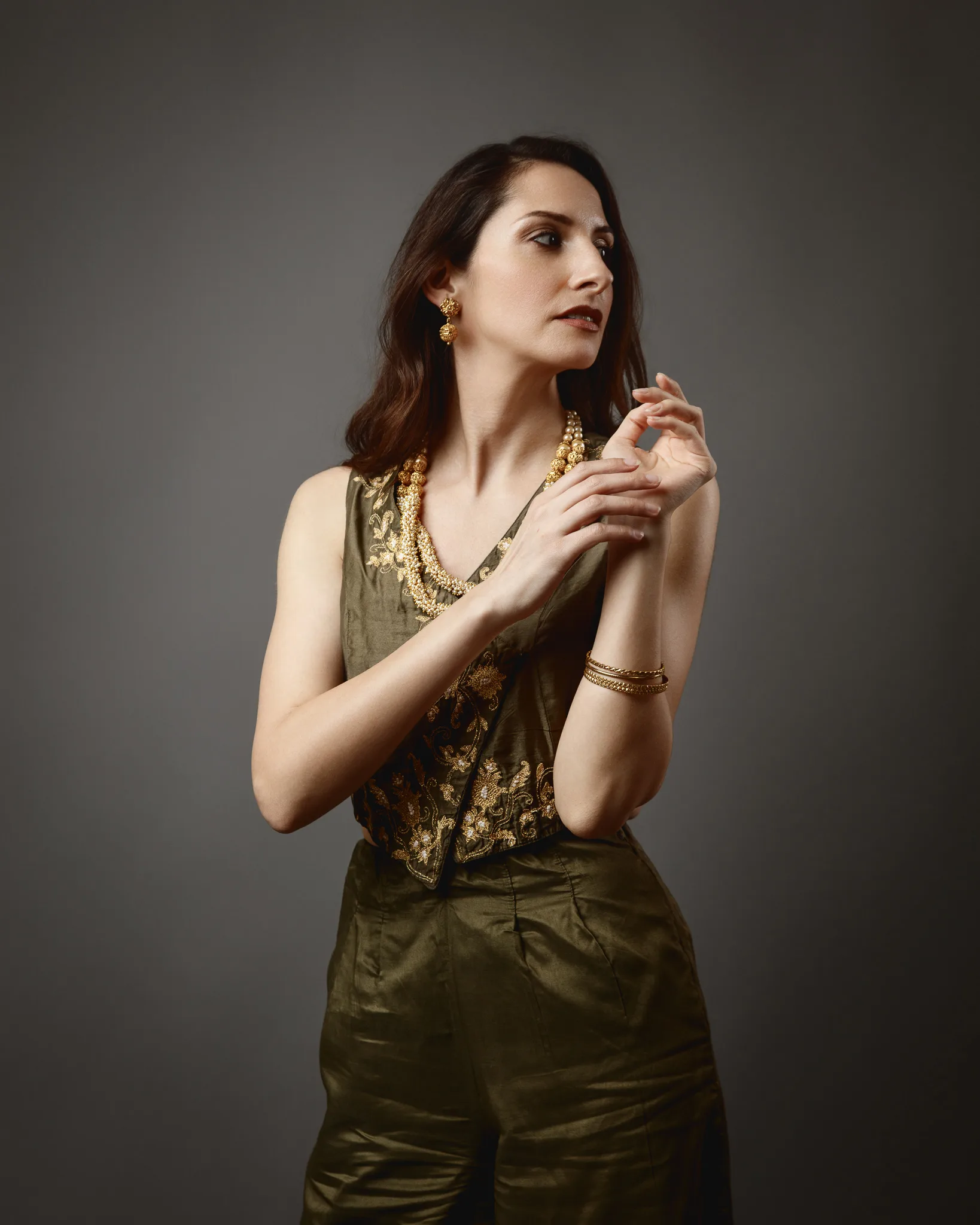 Woman in olive outfit with gold jewelry