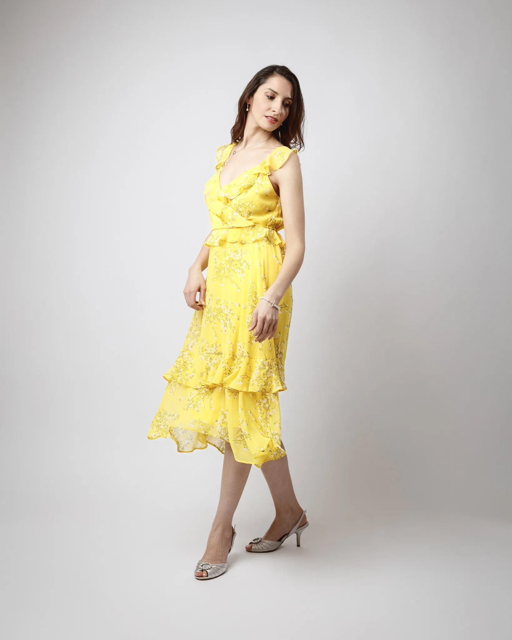 Woman in yellow floral dress posing elegantly