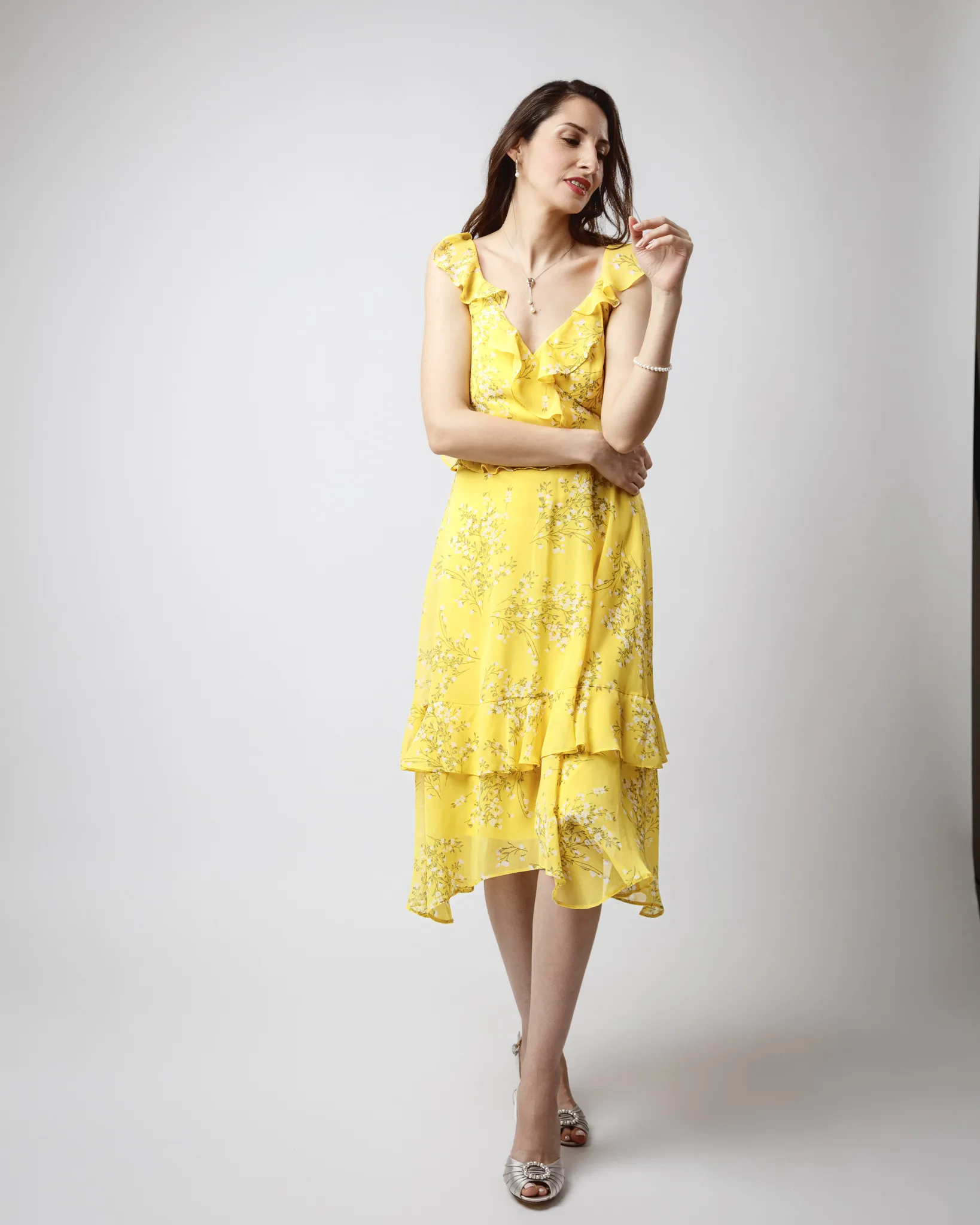 Woman in yellow floral dress posing confidently