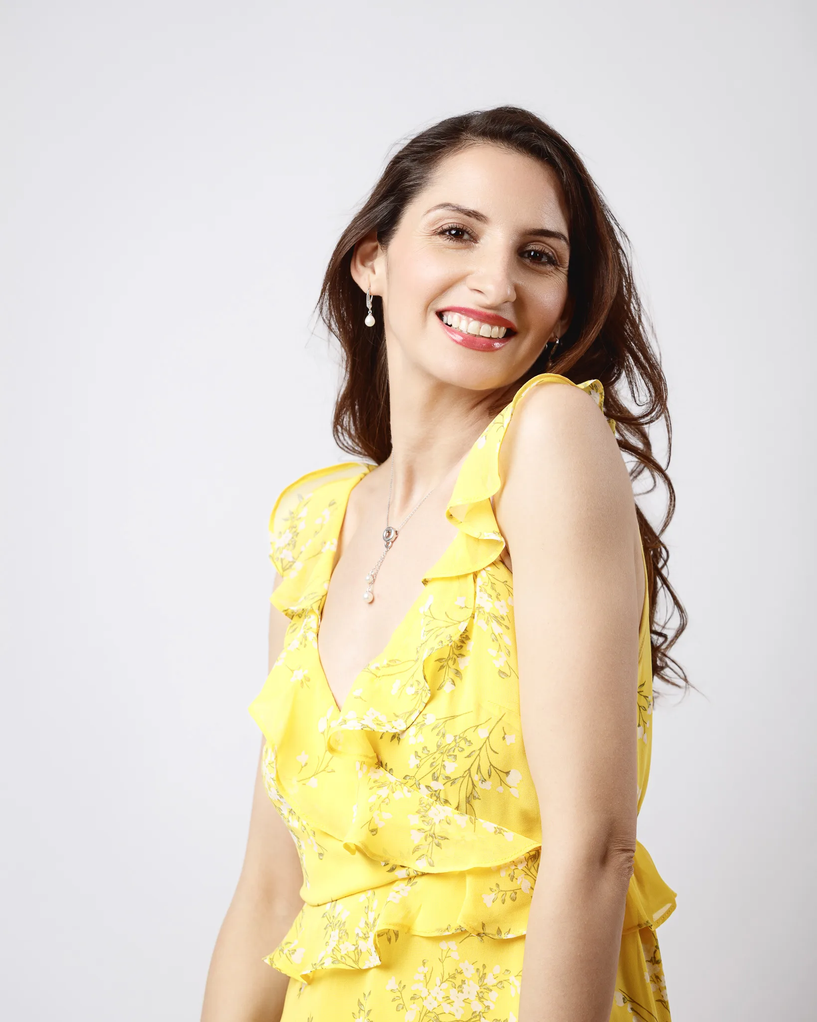 Smiling woman in yellow floral dress.