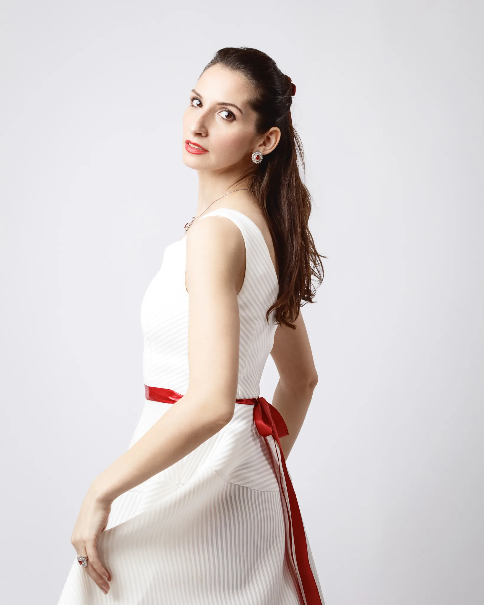 Woman in white dress with red ribbon