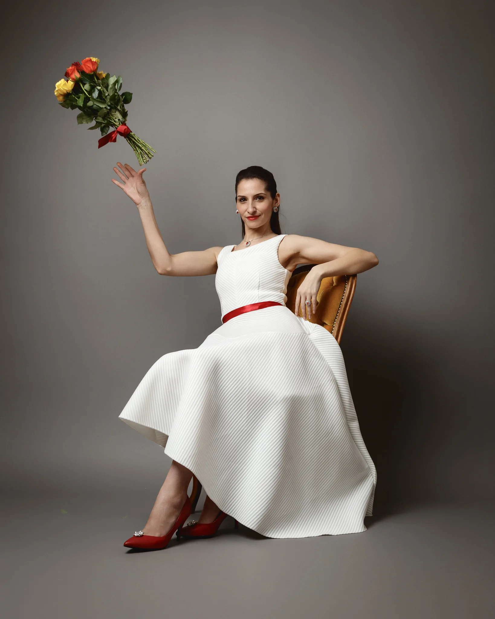 Woman in white dress holding flowers aloft