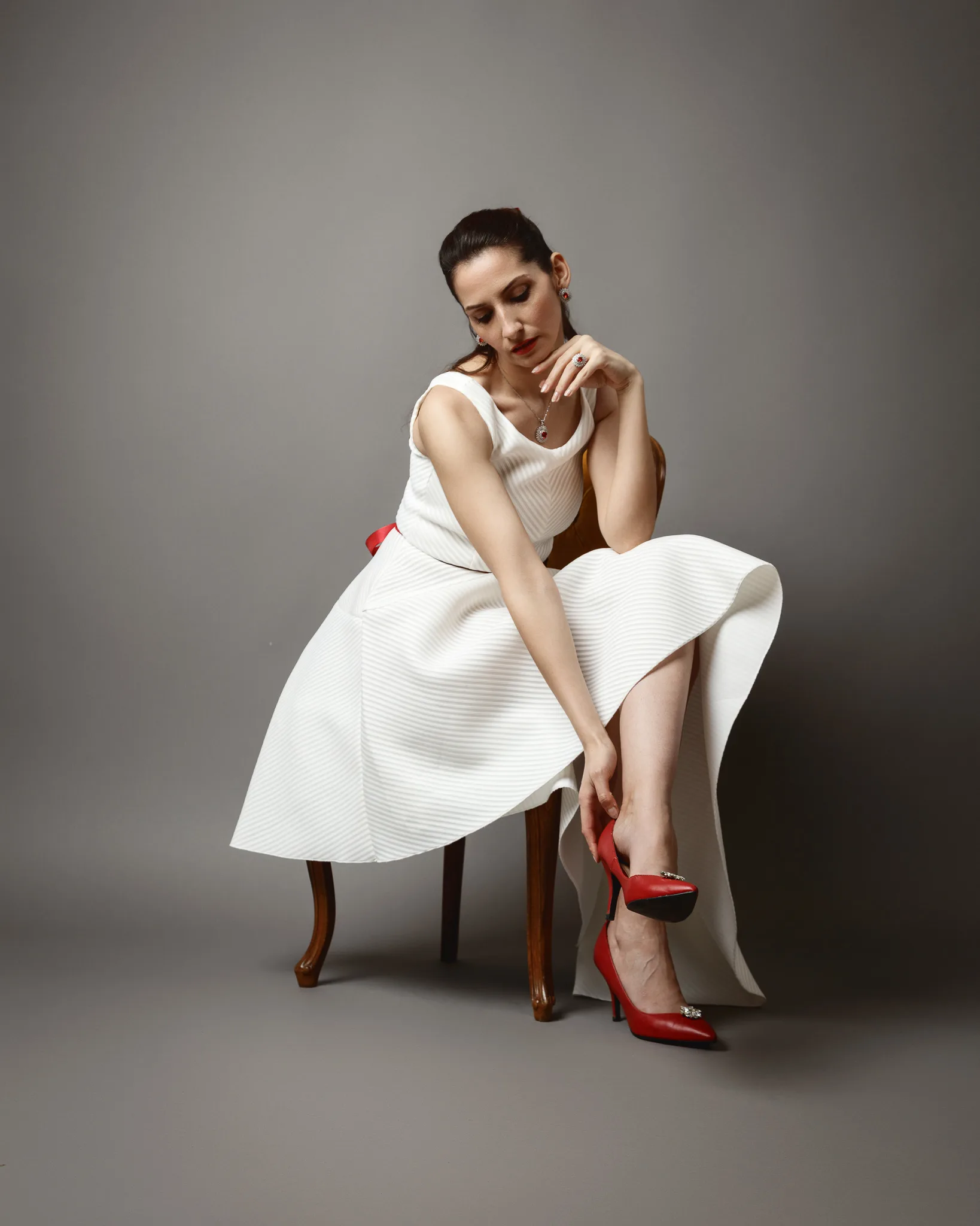 Woman in white dress adjusting red shoes