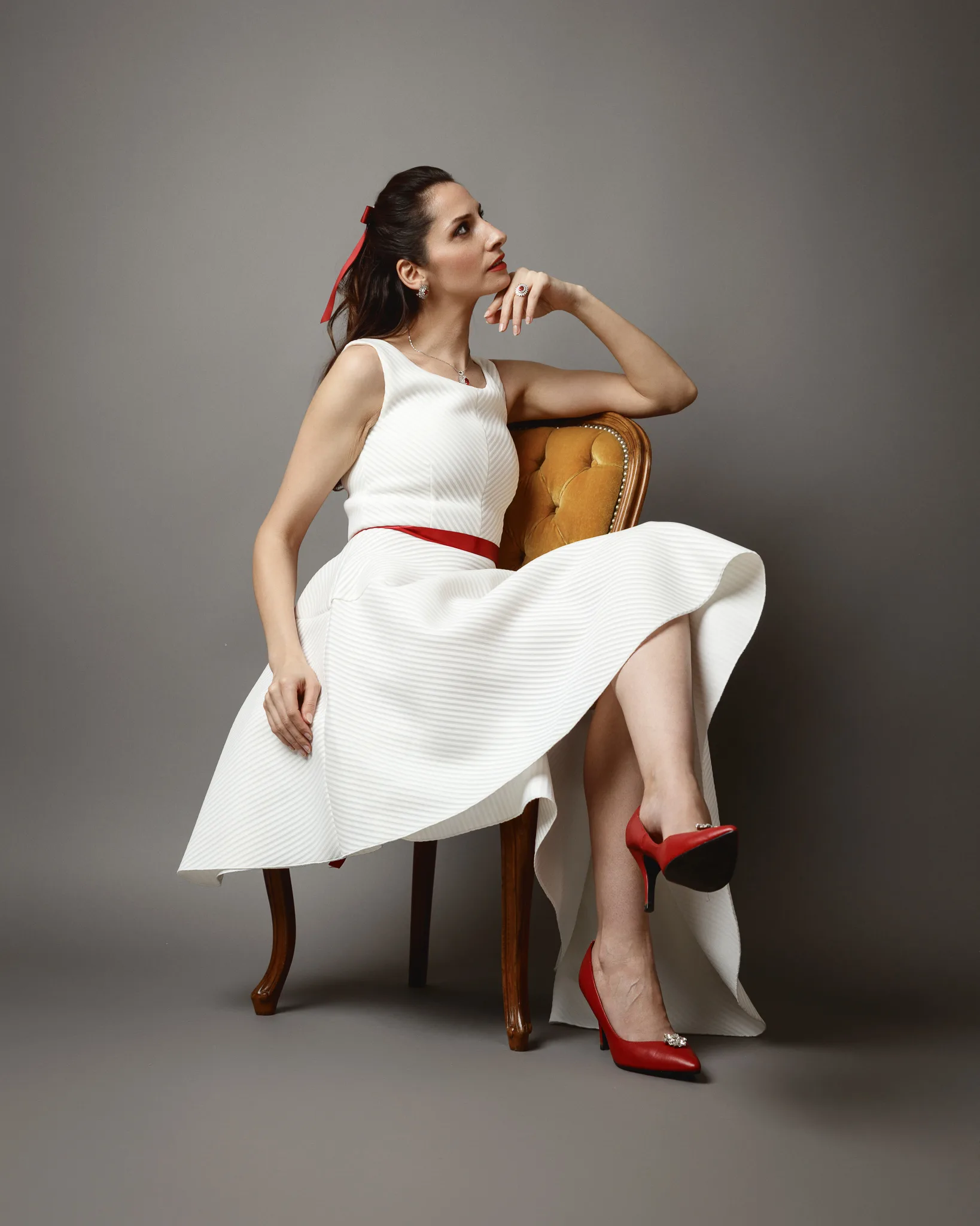 Woman in white dress and red shoes sitting