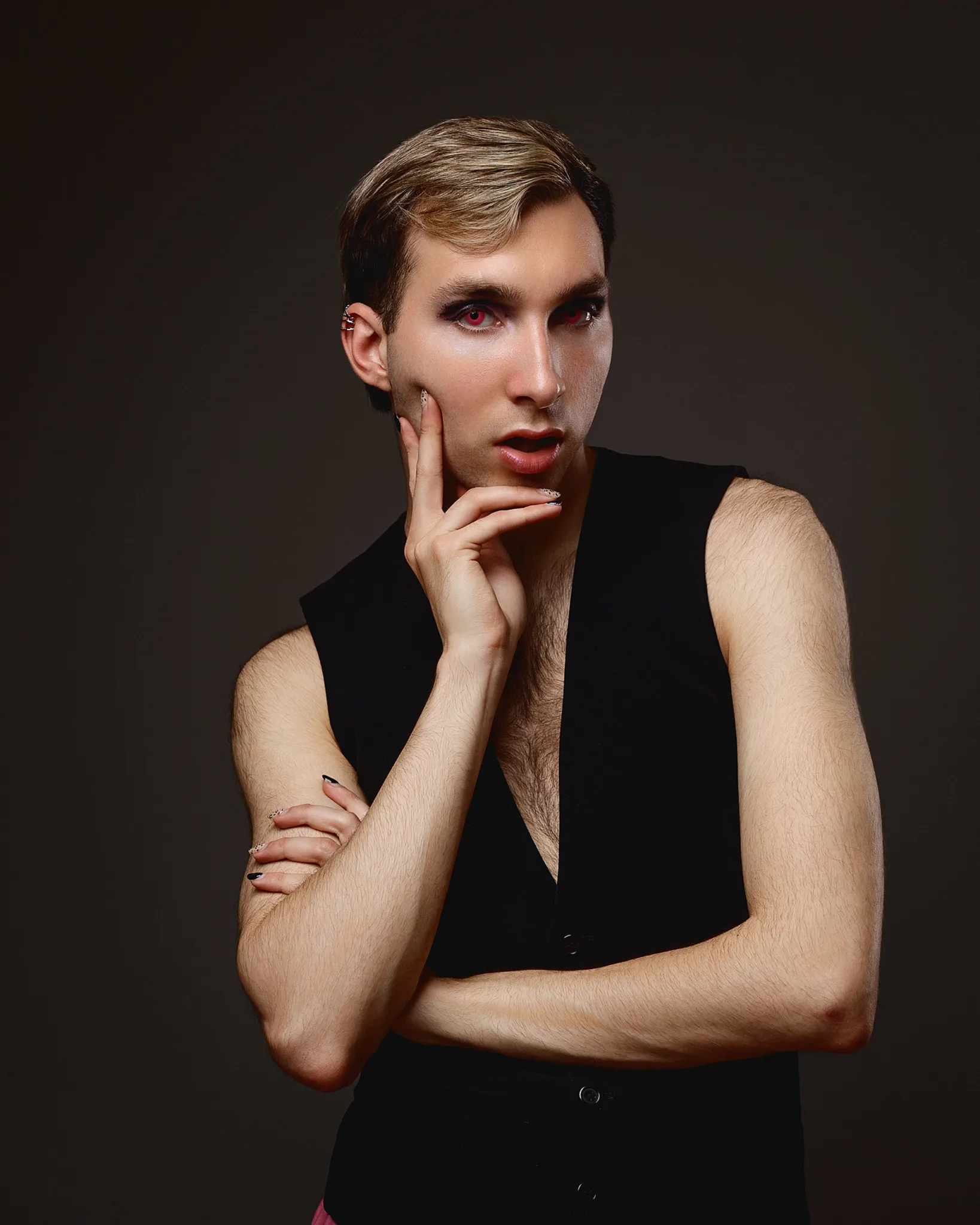 Person with makeup in black vest posing