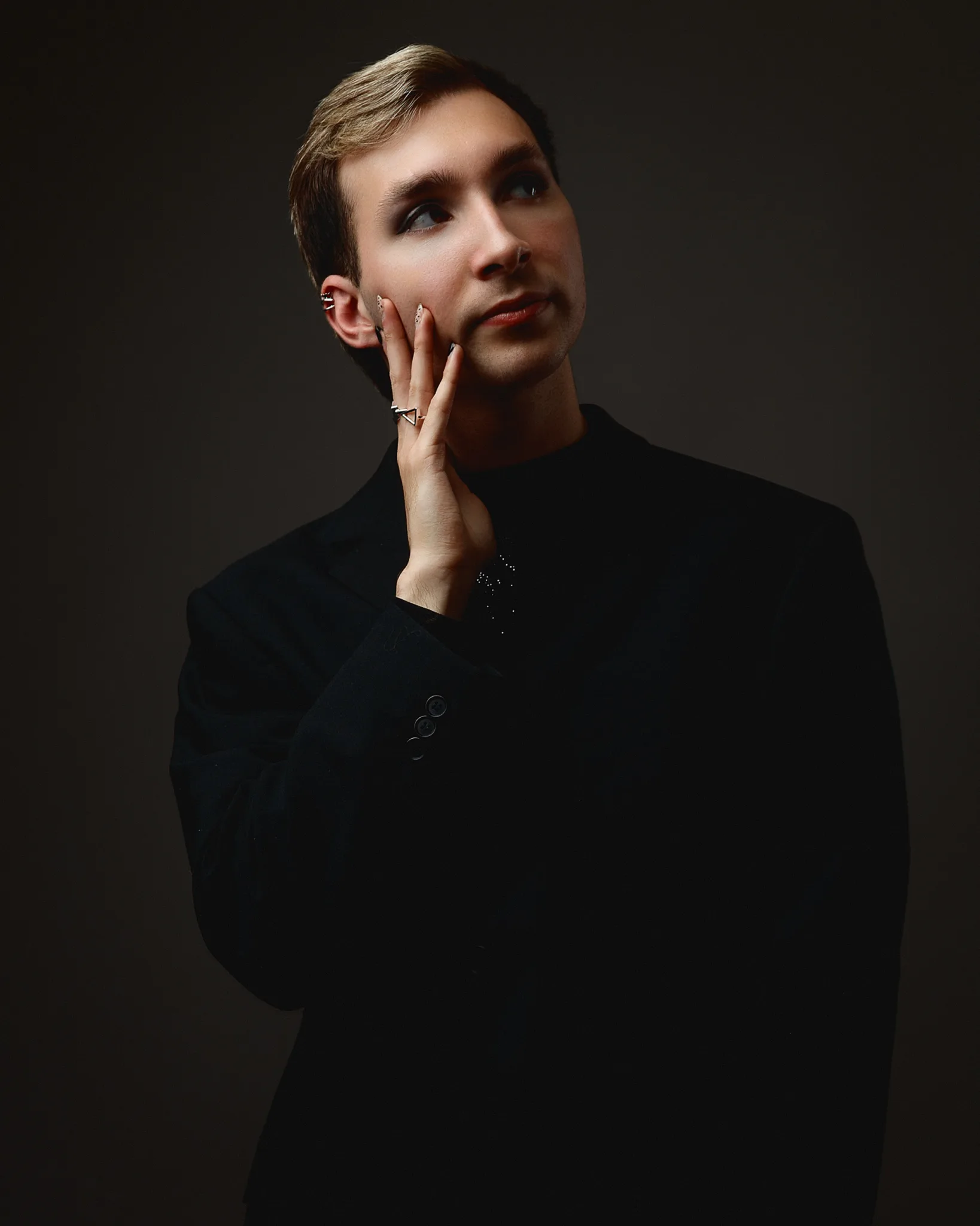 Person posing in dark suit with thoughtful expression