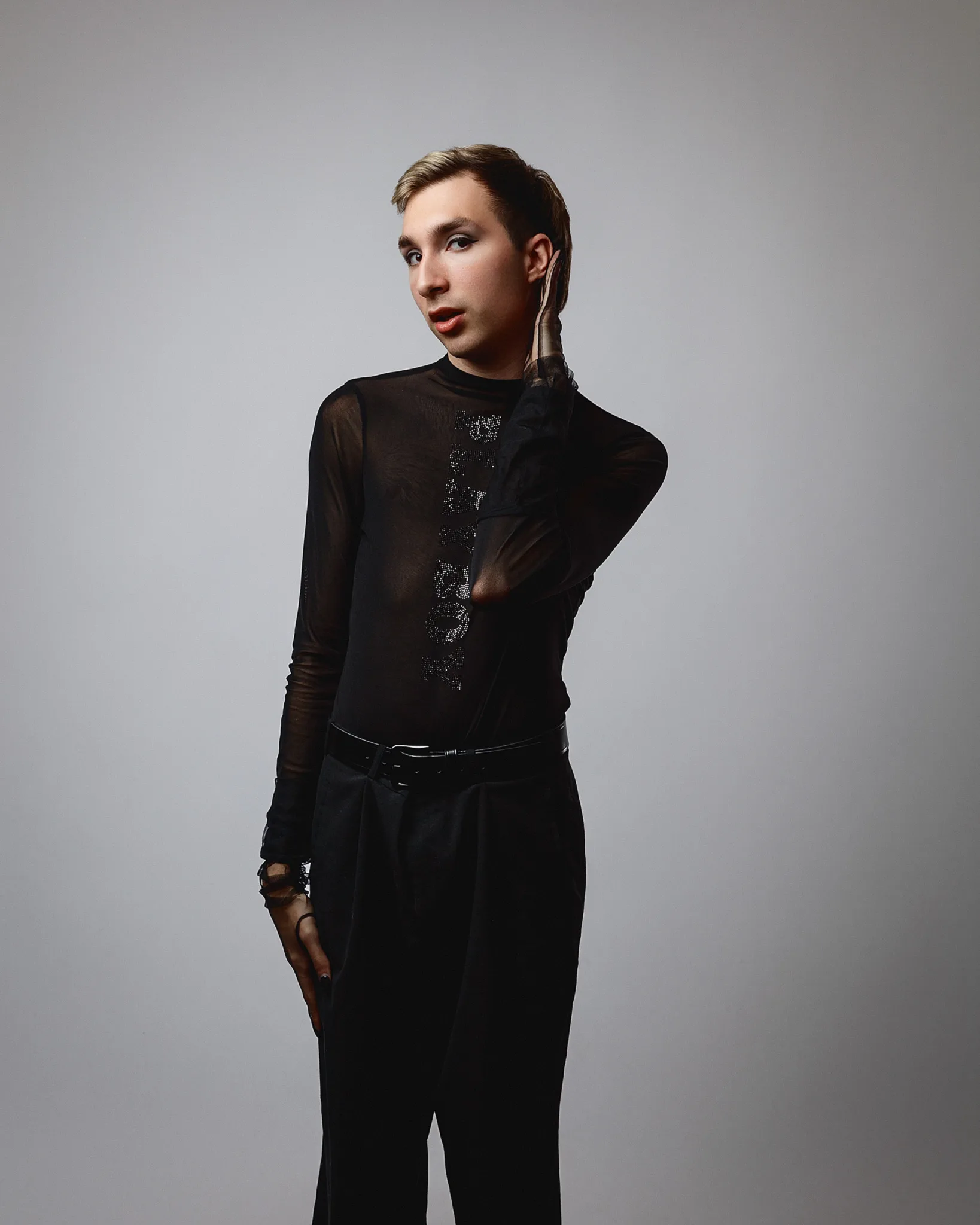 Person in black sheer top posing gracefully.