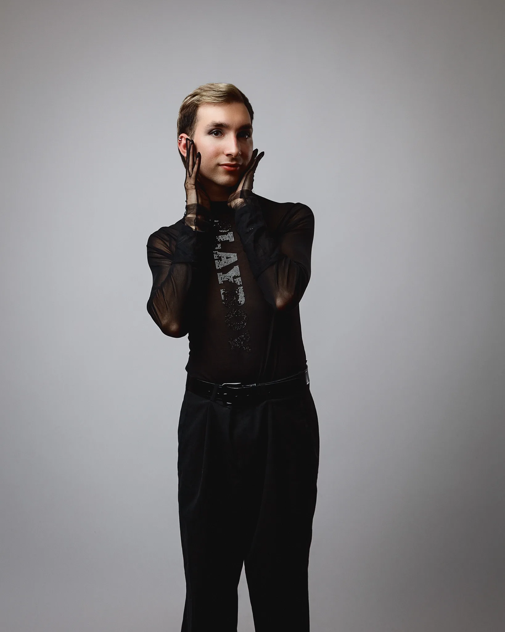 Person posing in dark, sheer clothing.