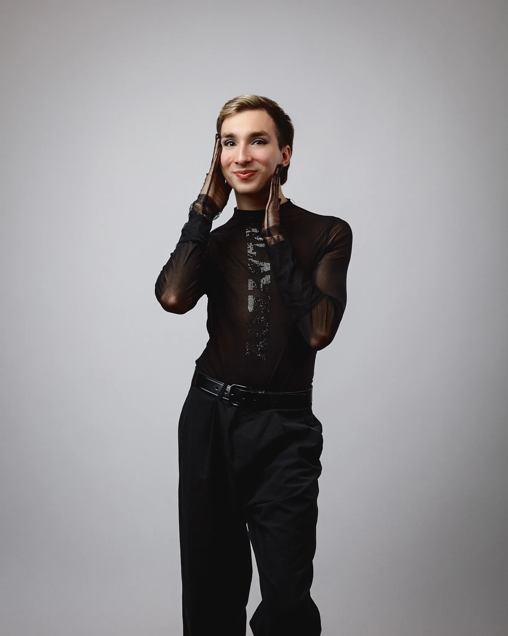 Person posing in black outfit, smiling