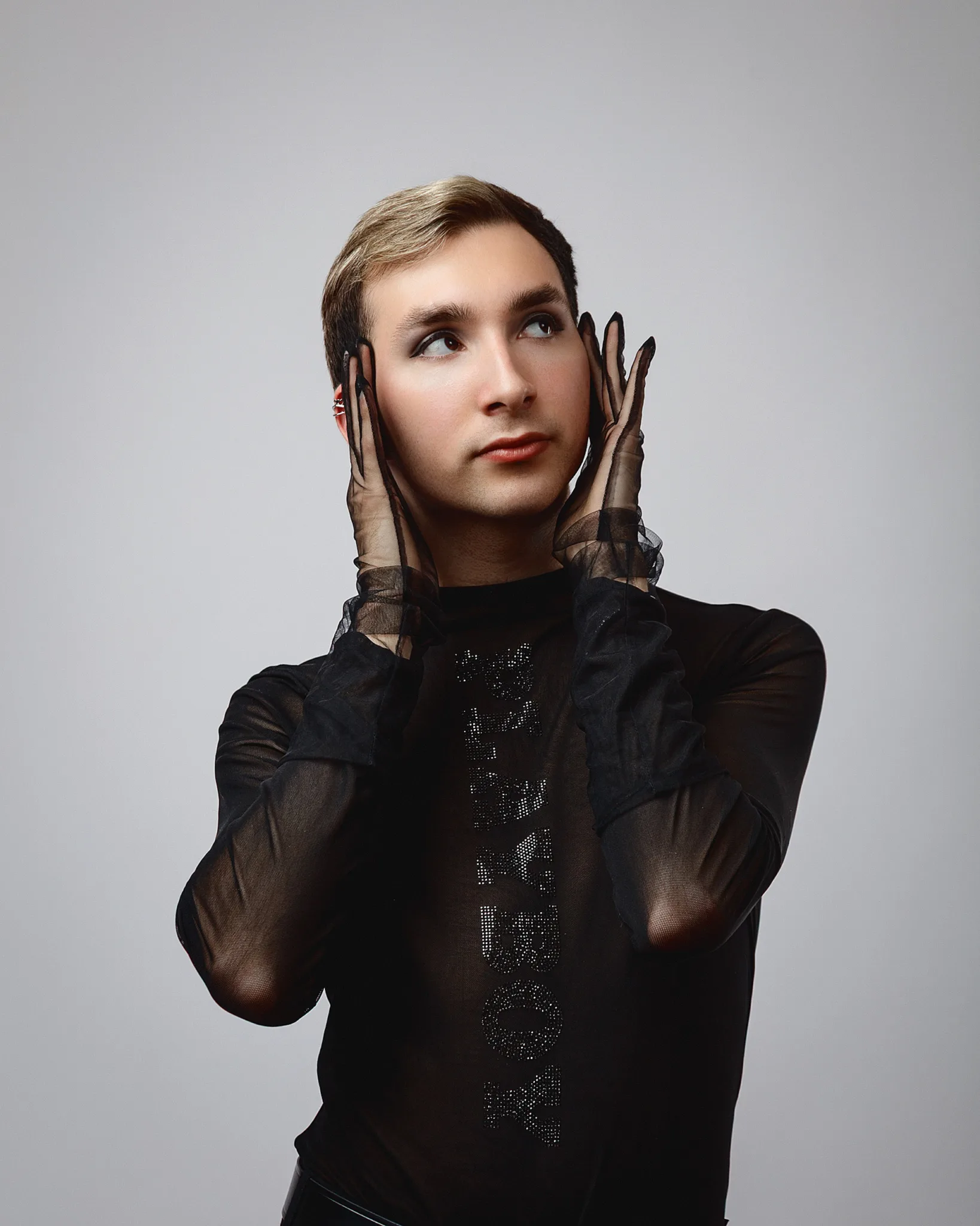 Person in sheer black top posing thoughtfully