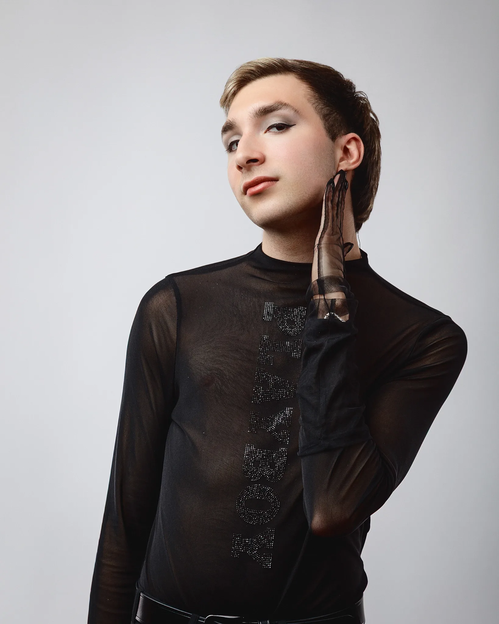 Person in black sheer top posing elegantly.