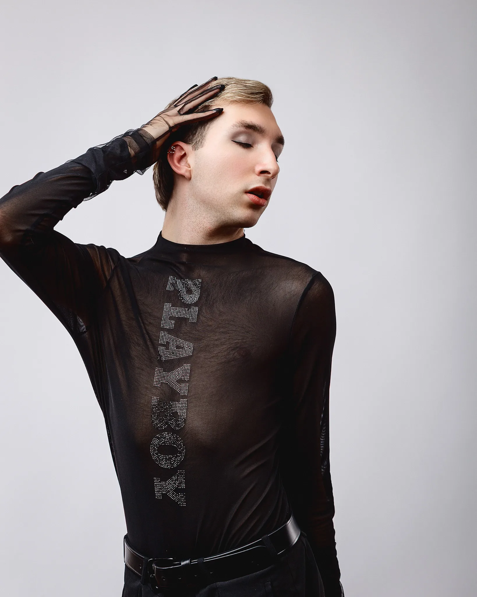 Person in black sheer top posing stylishly