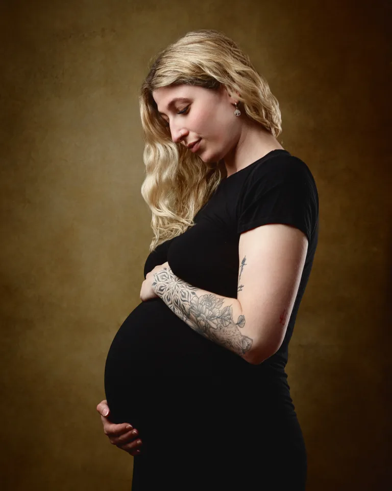 Pregnant woman in black dress, studio portrait