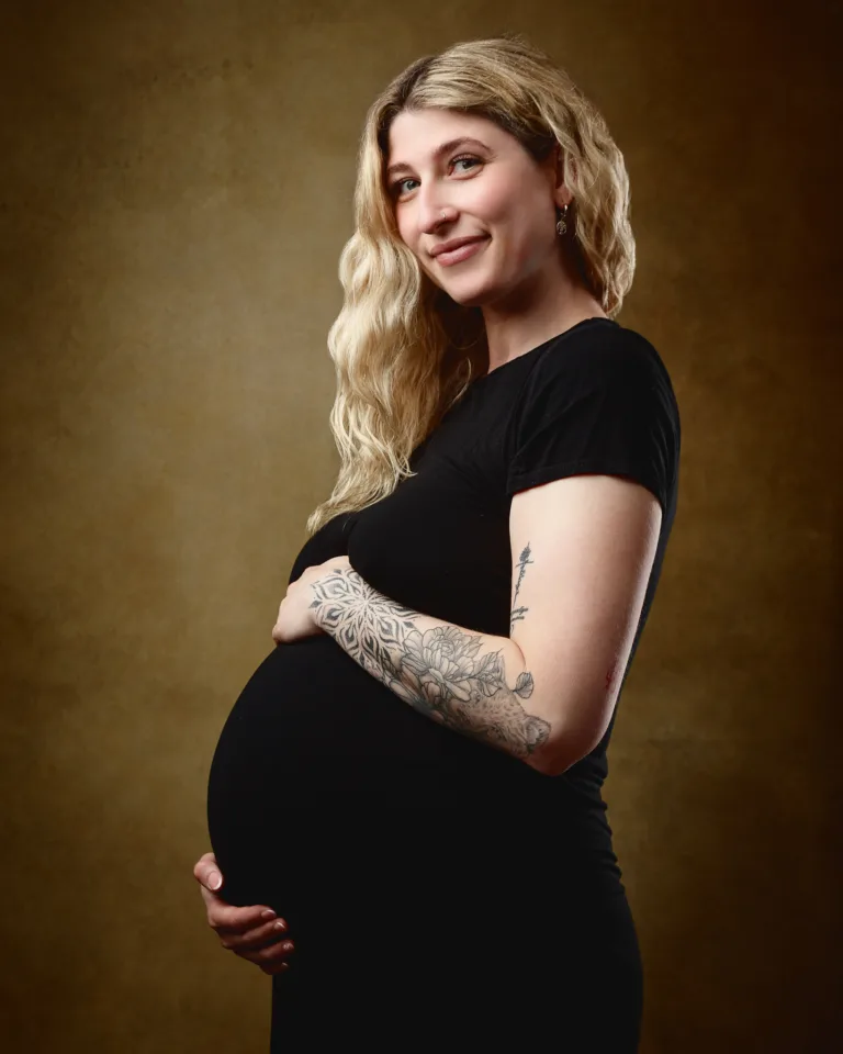 Pregnant woman in black dress, studio portrait