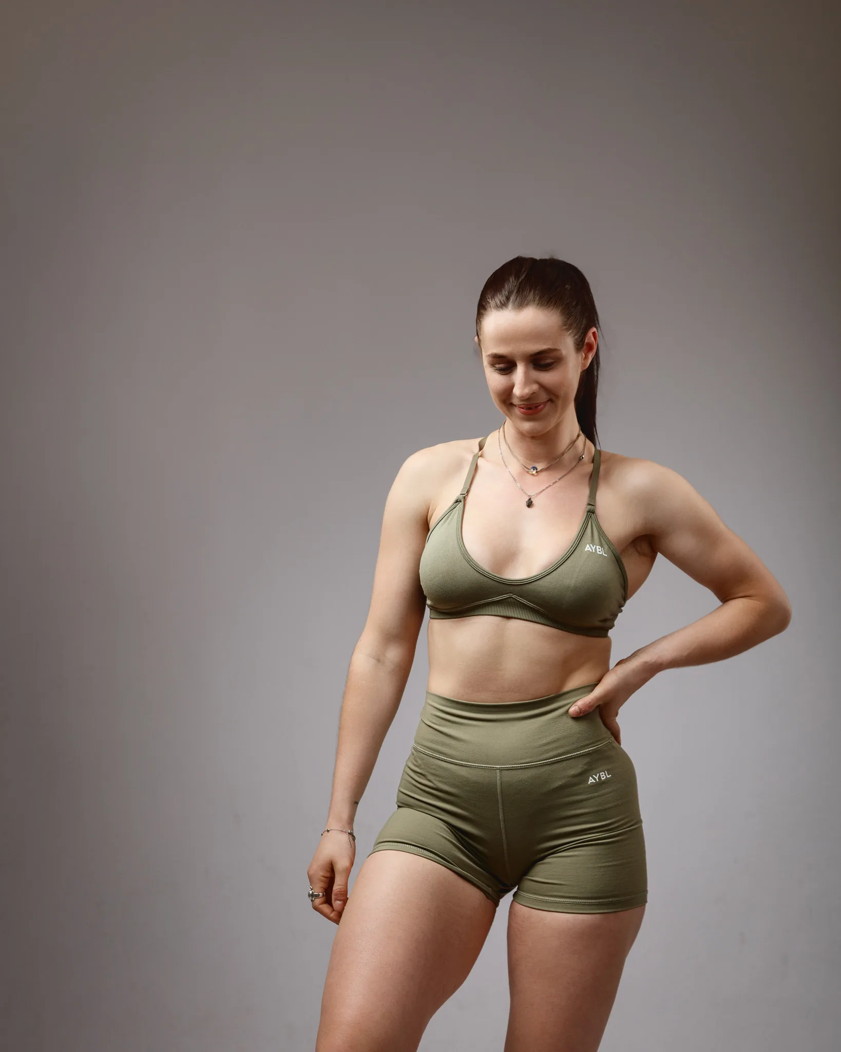 Woman in olive green sportswear posing indoors