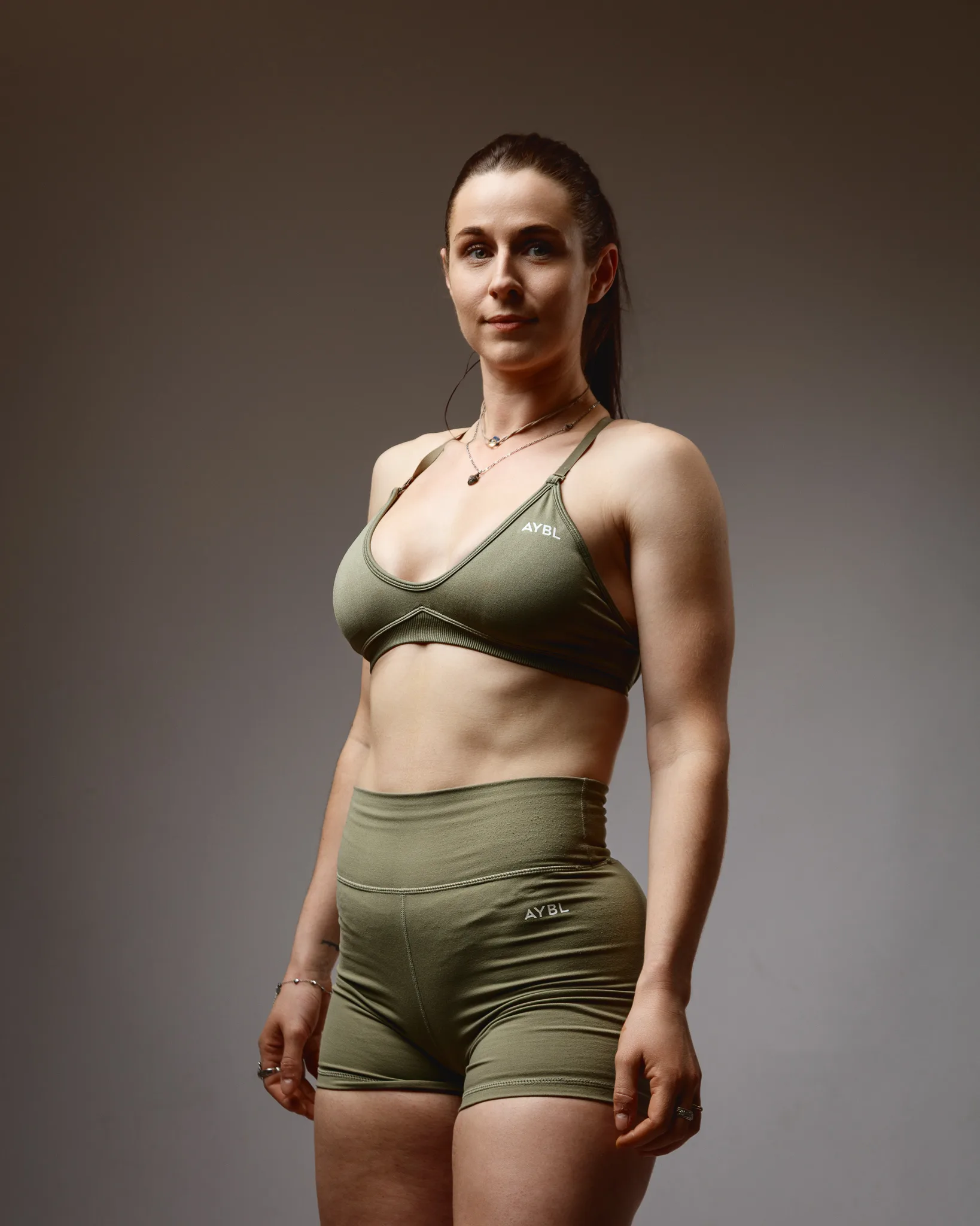 Woman in olive green gym wear posing