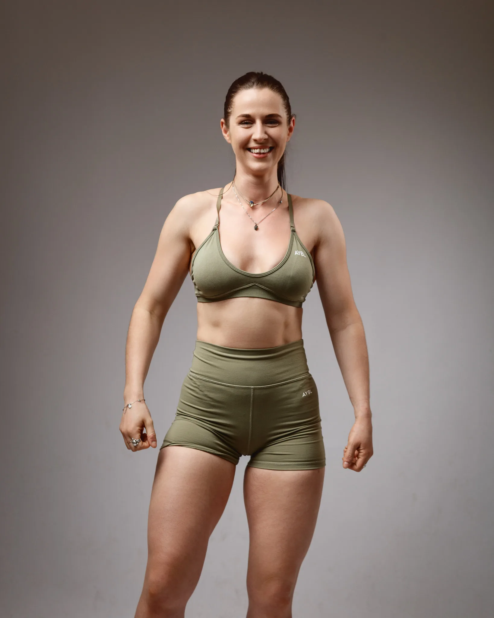 Woman in olive green sportswear smiling in studio
