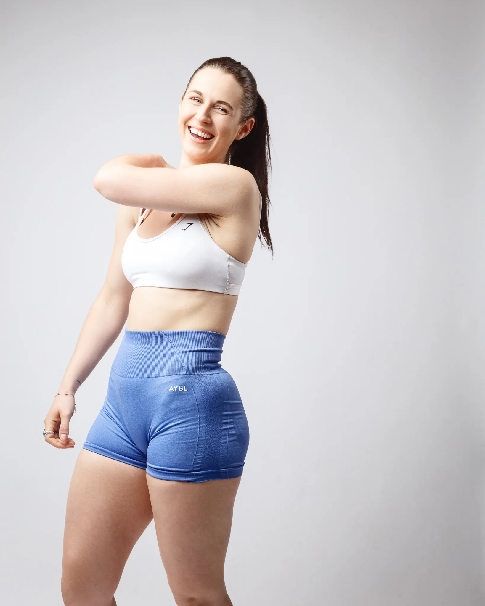 Woman in sportswear stretching and smiling in studio