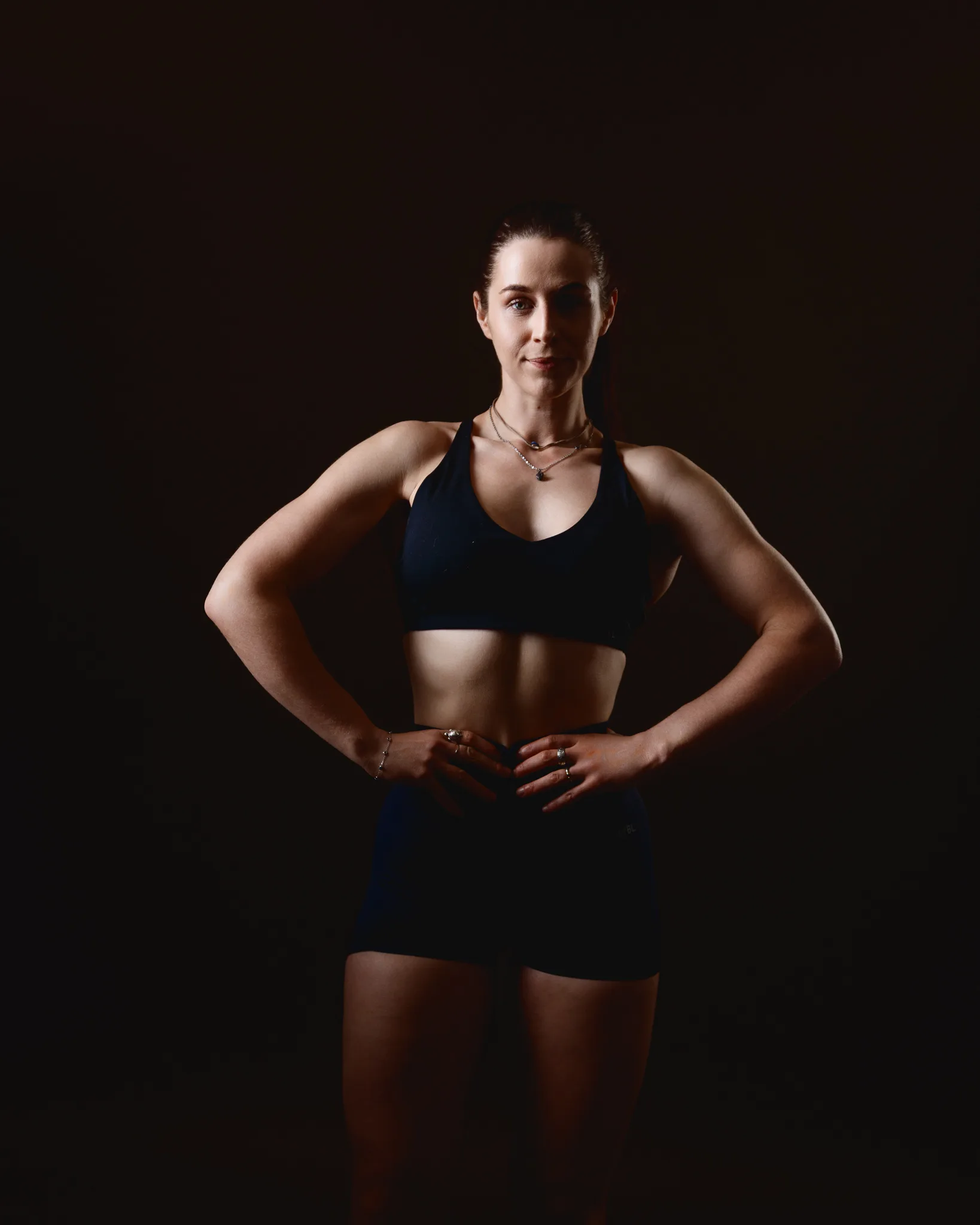 Athletic woman posing in sportswear against dark background