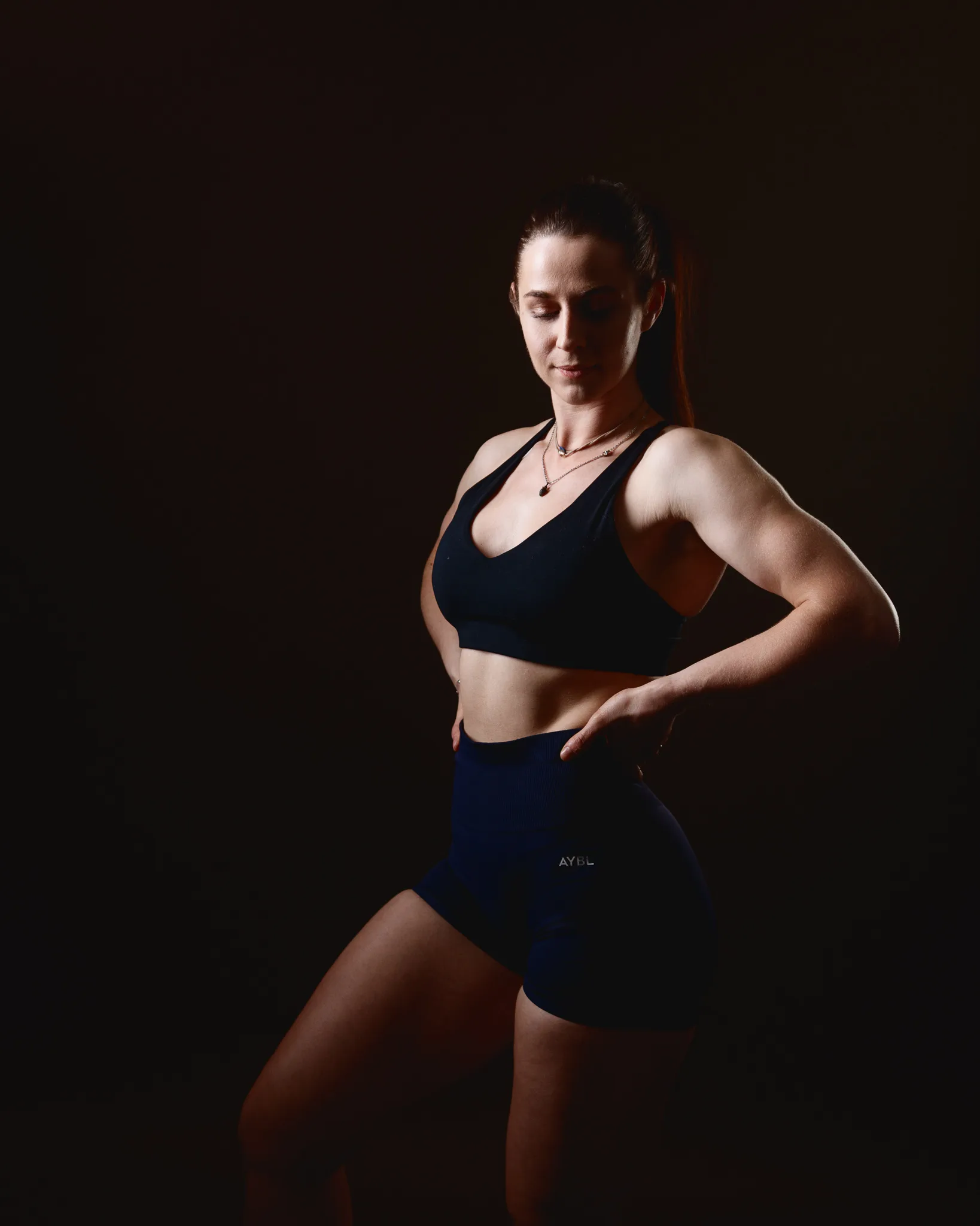 Woman in black sportswear posing in studio lighting