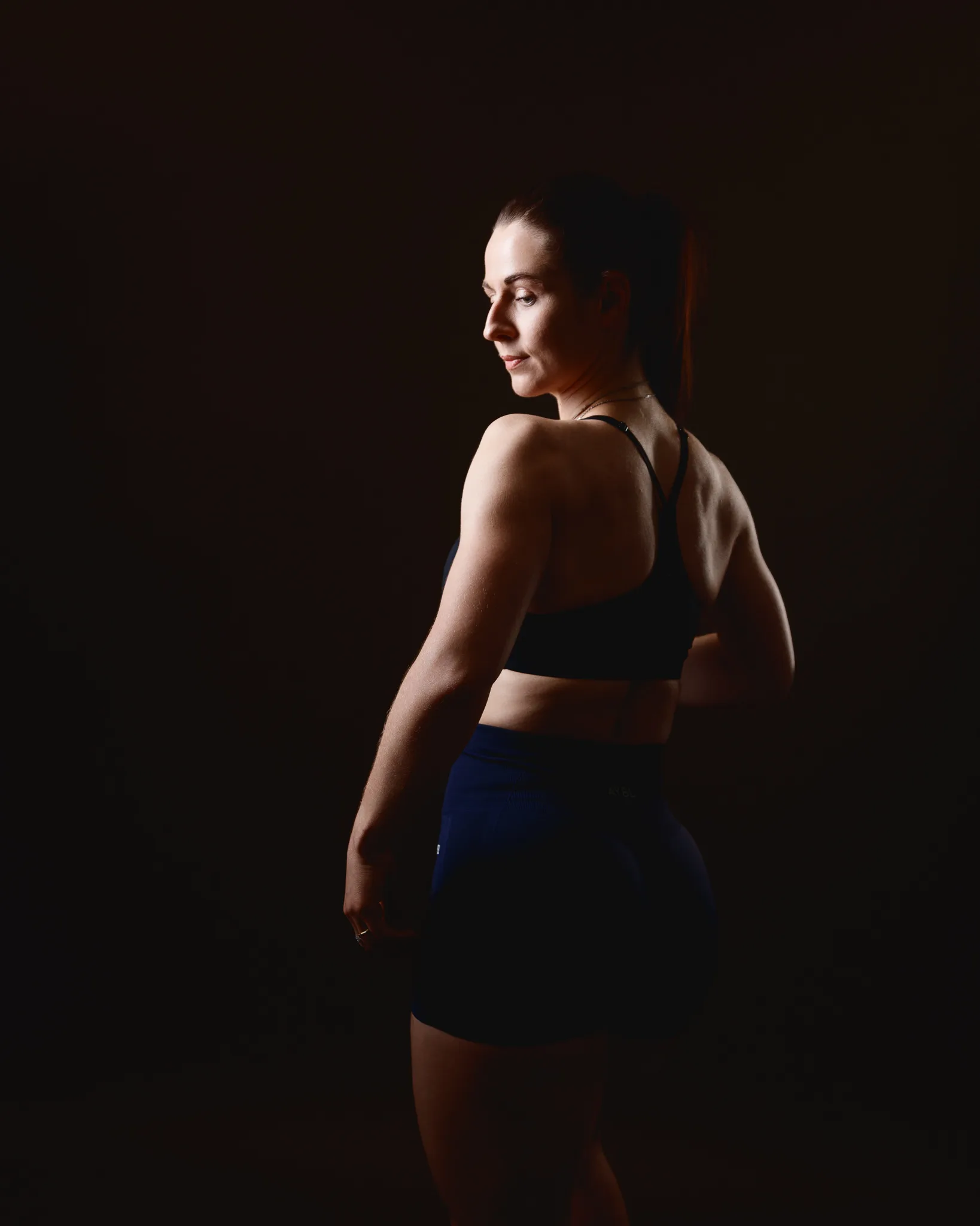 Woman in sportswear posing against dark background