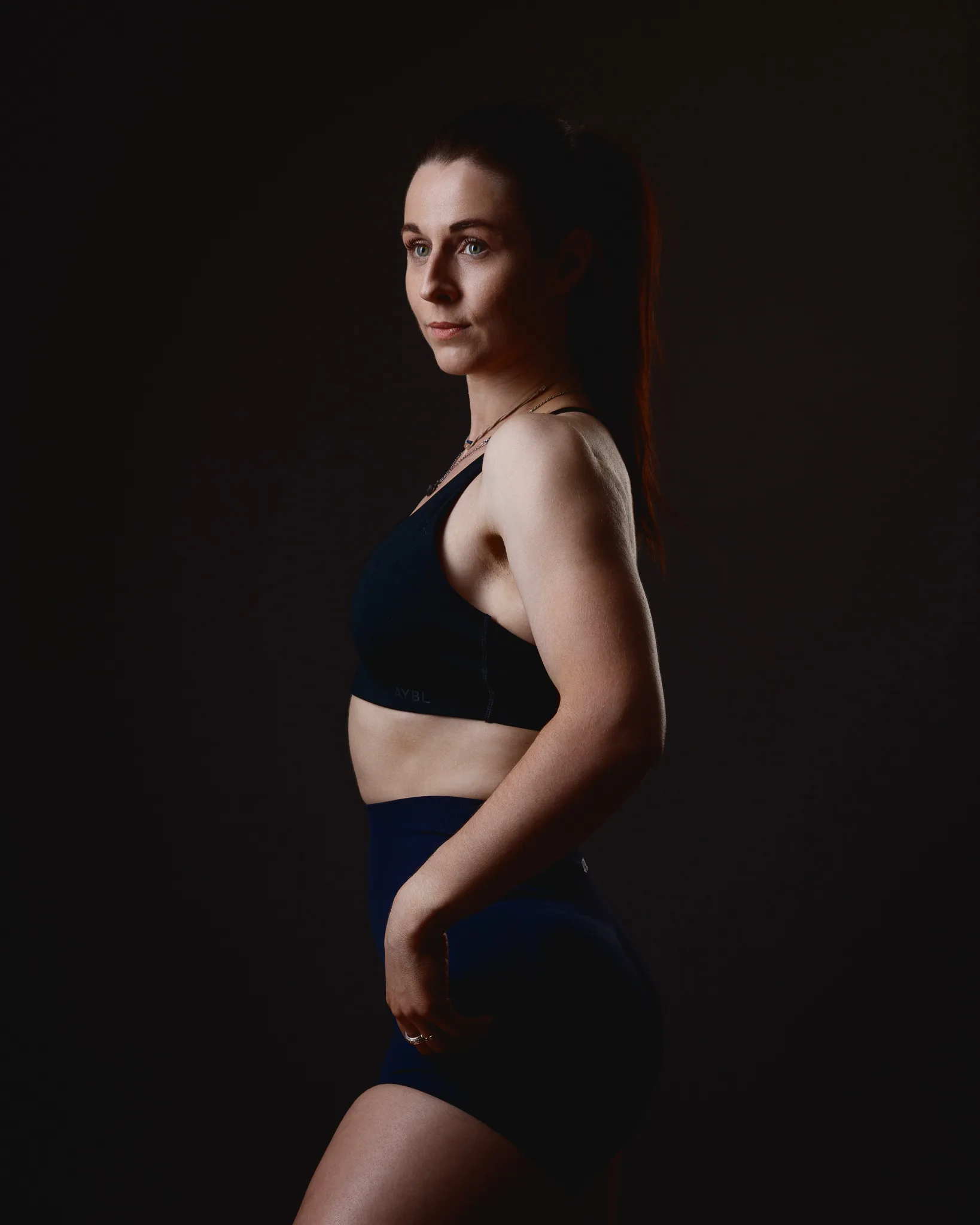 Side profile of woman in sportswear against dark background