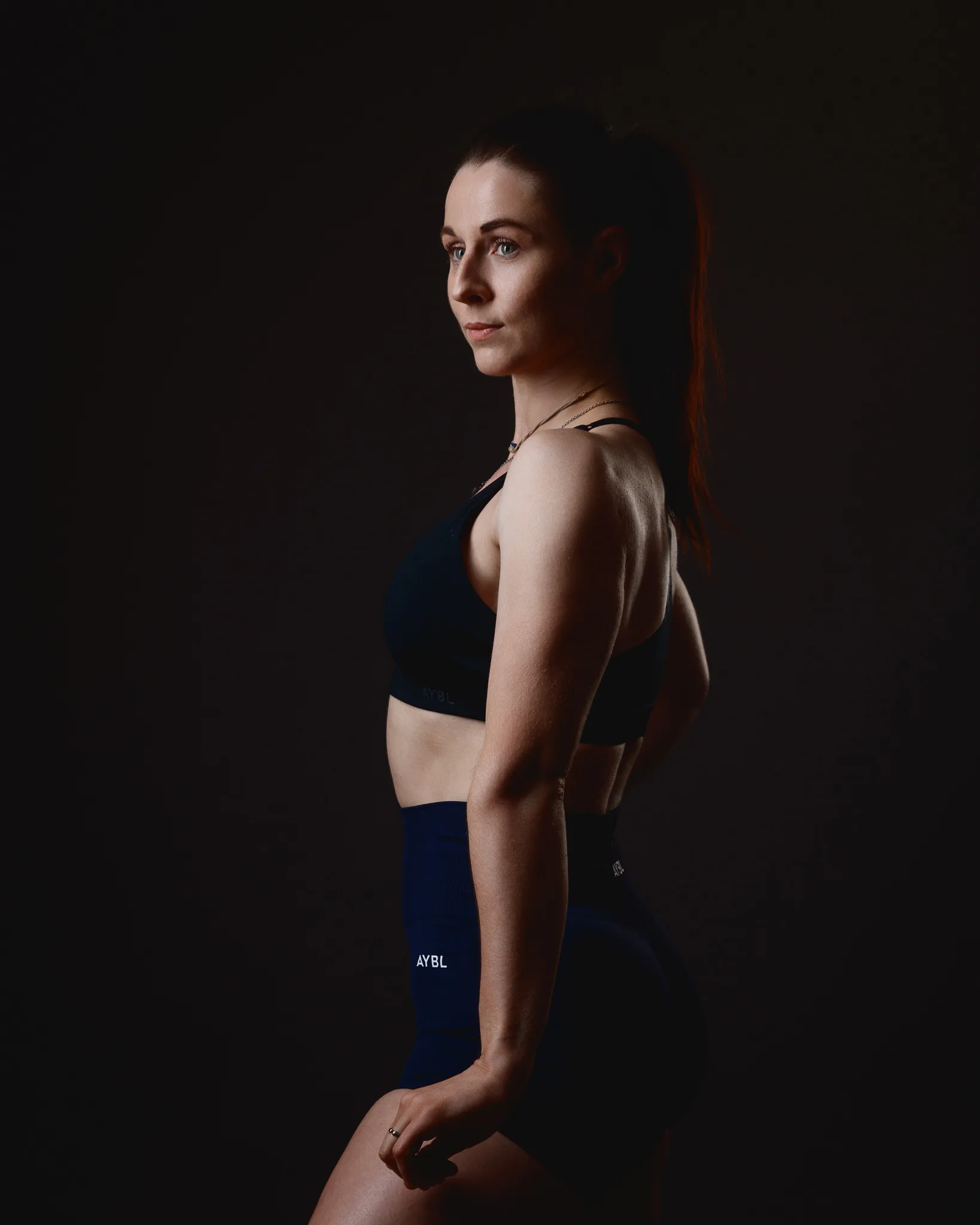 Woman in sportswear posing against dark background
