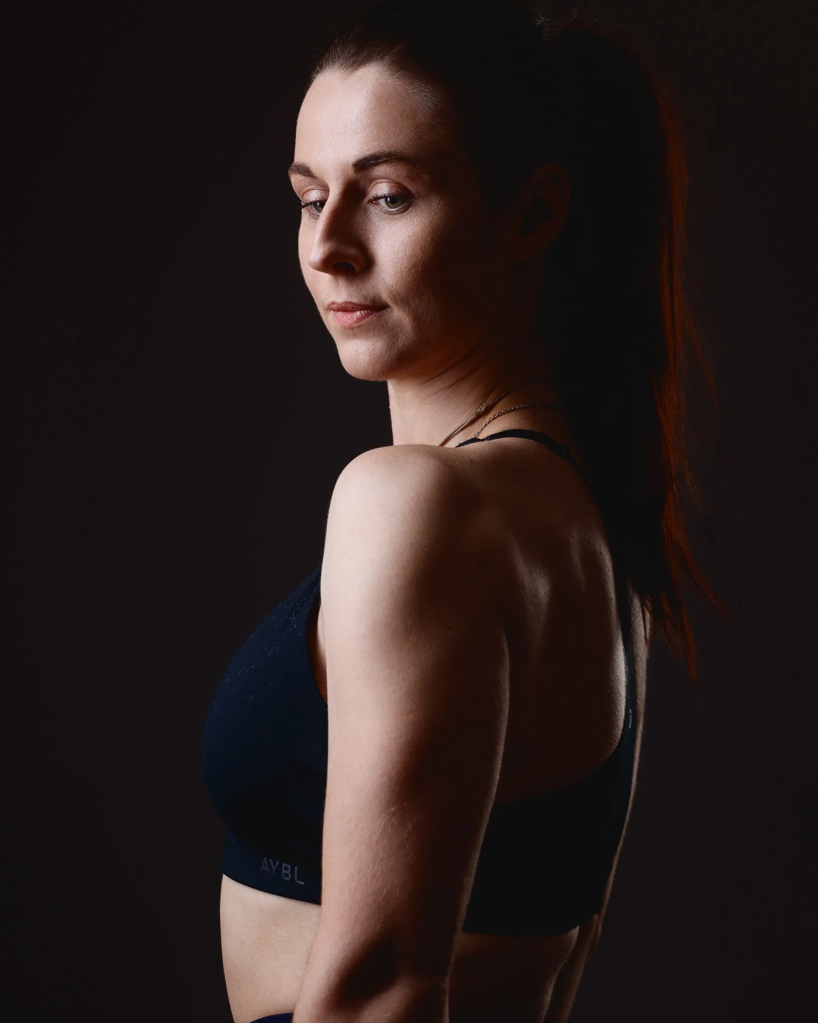 Woman in sports bra under dramatic studio lighting
