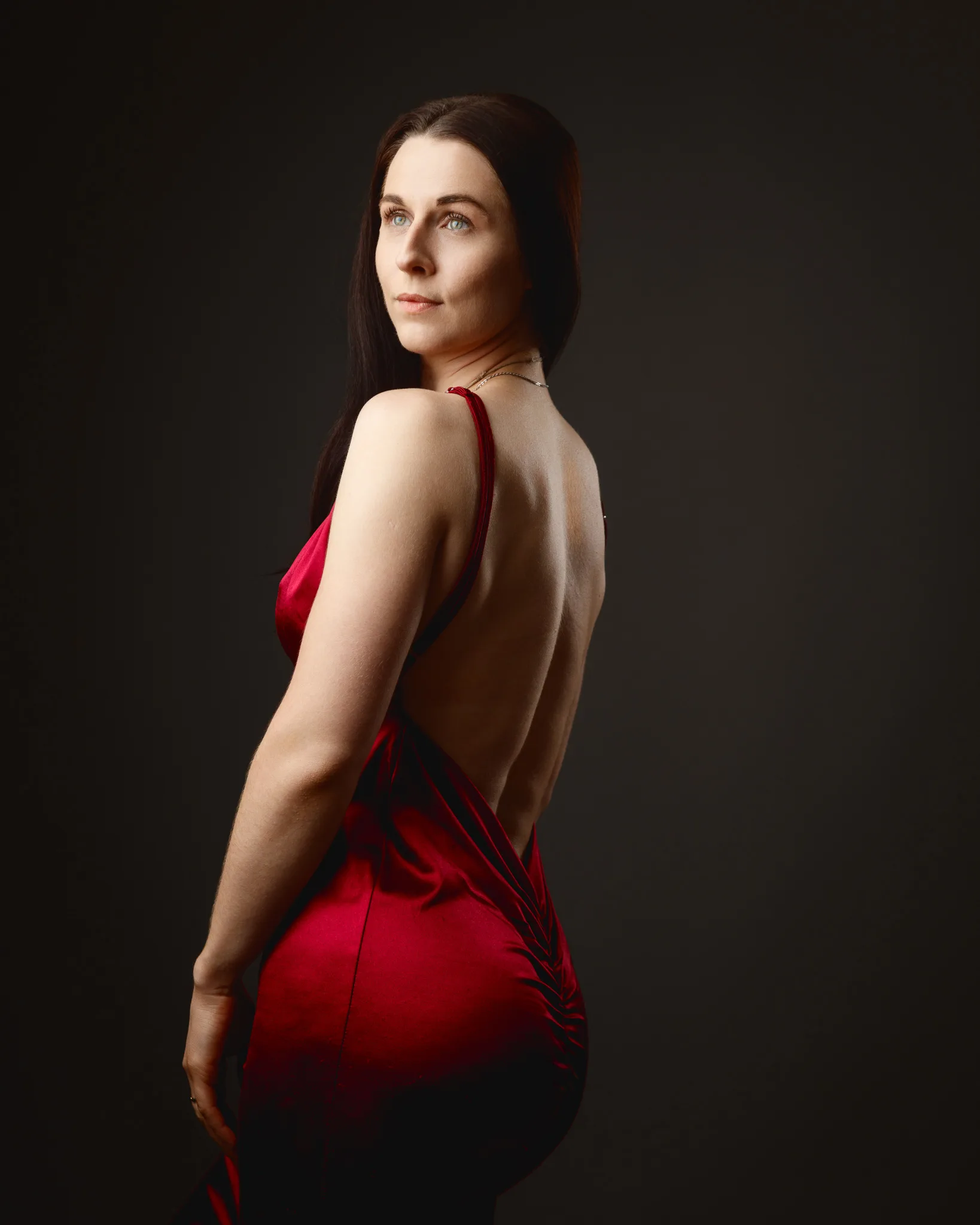 Woman in red backless dress looking over shoulder