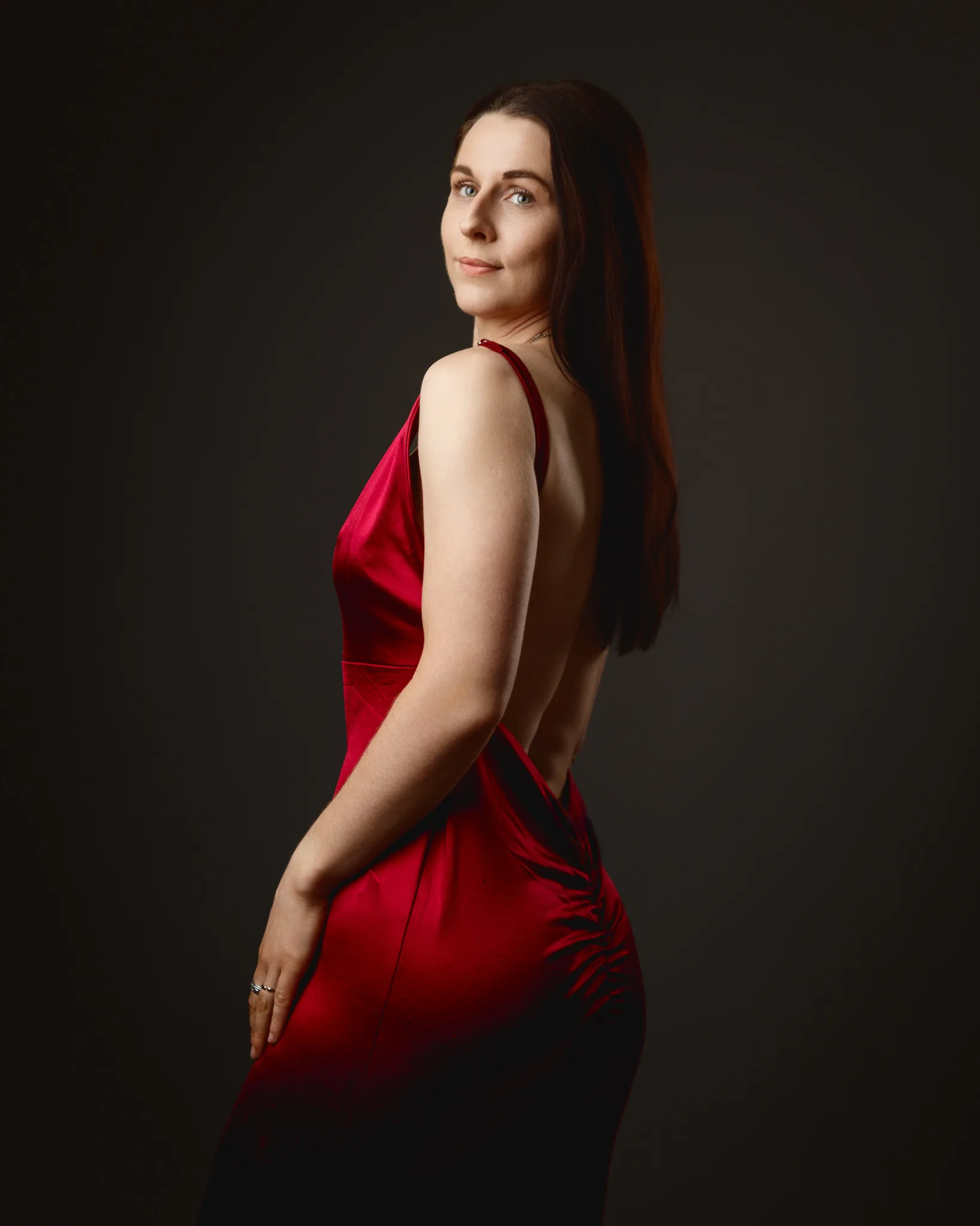 Woman in red backless dress, studio portrait
