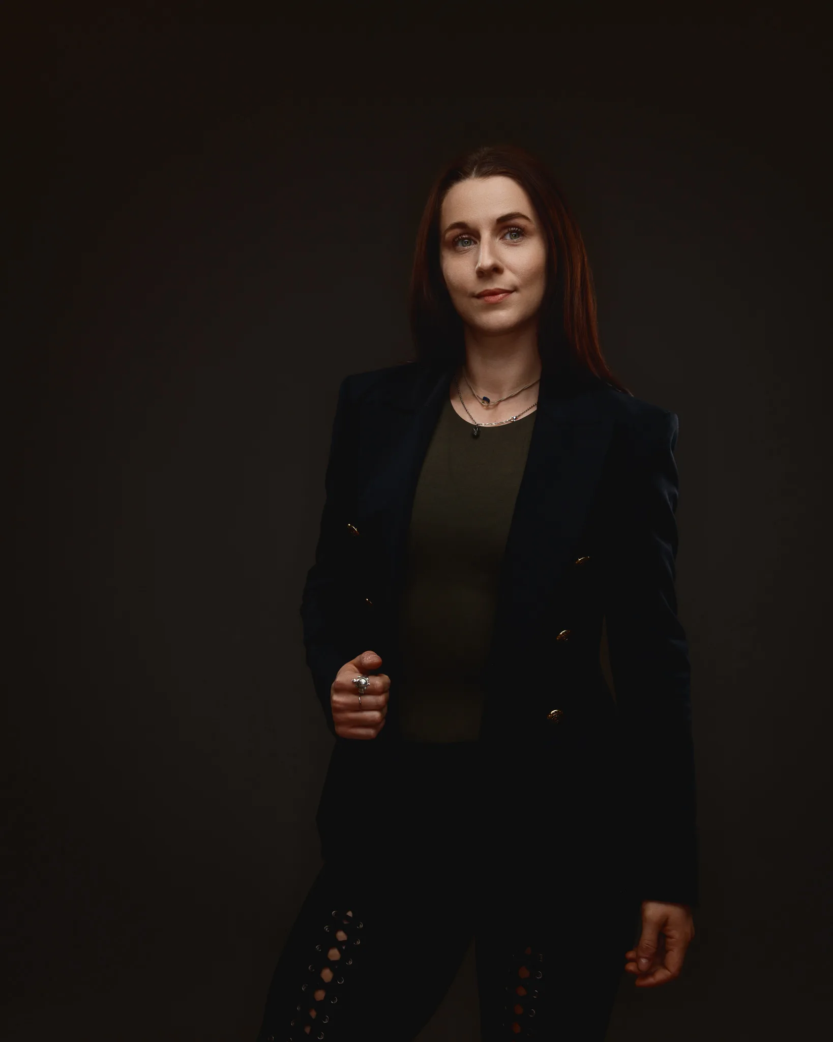 Woman in dark blazer posing against plain background