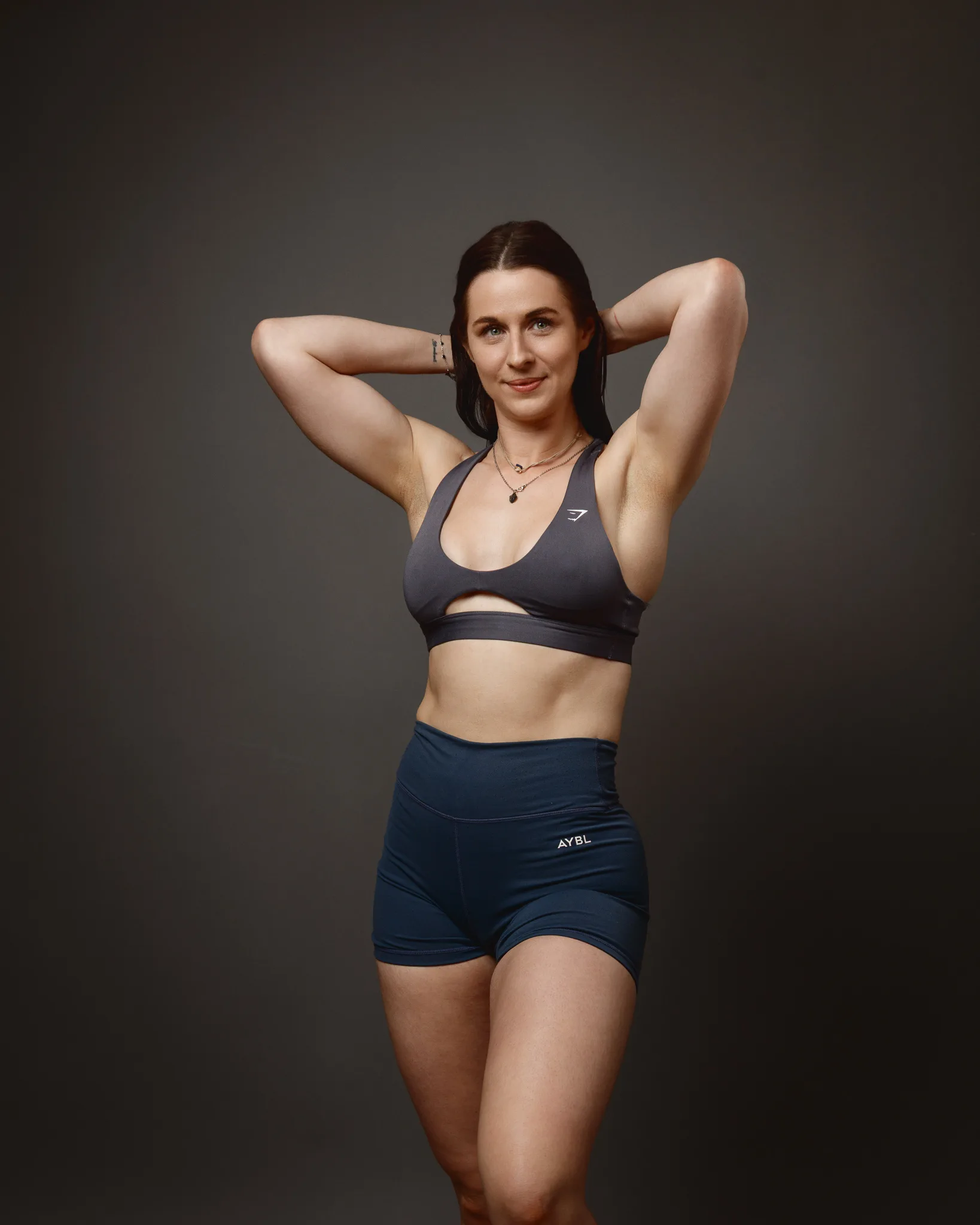 Woman in sportswear posing against dark studio background