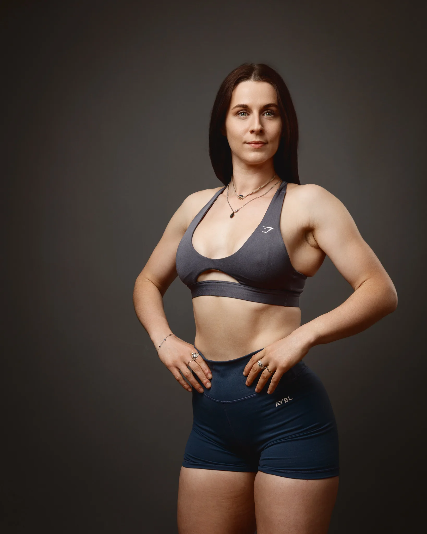 Woman in sportswear posing against dark studio background