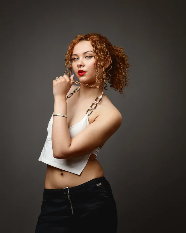 Woman with curly hair holding gold chain necklace